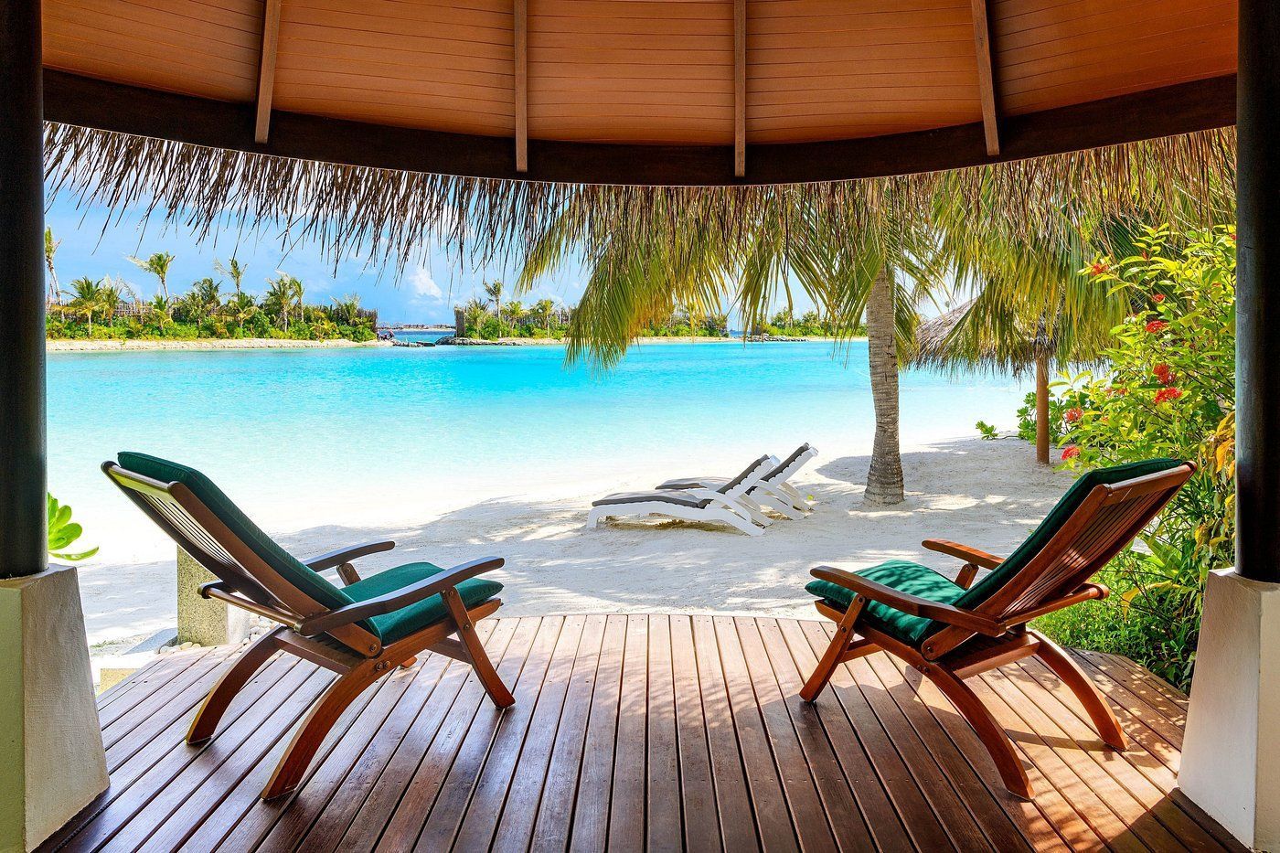 Terasa cu 2 șezlonguri a hotelului Sheraton Maldives Full Moon Resort & Spa. Terasa se prelungește direct pe plaja insulei și spre golful oceanului.