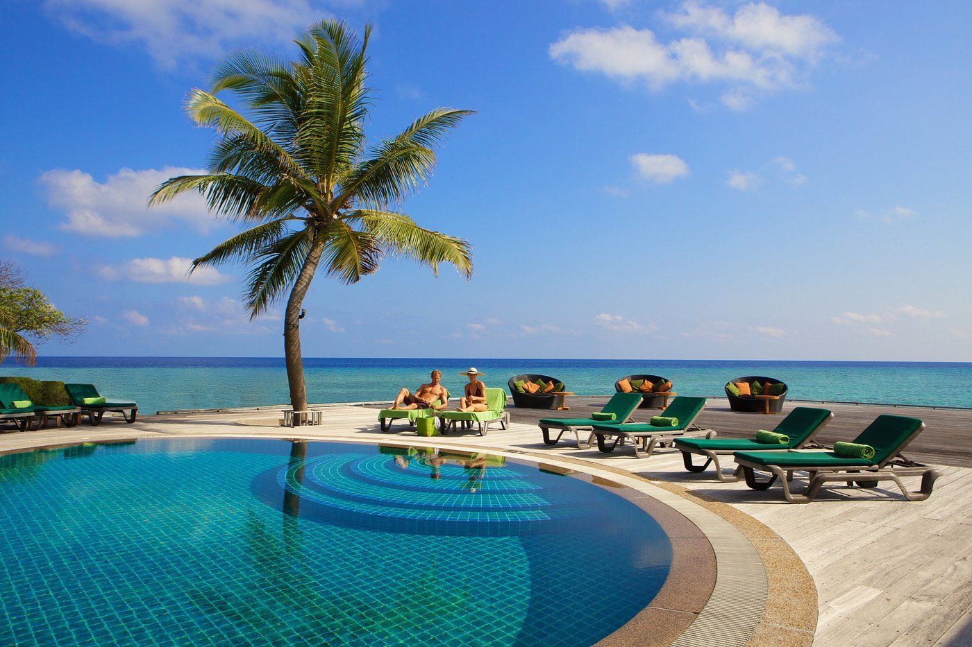 Piscina privată a resortului de lux Kuredu Island Resort & Spa. Are zonă de șezlonguri și palmieri și este lângă ocean.