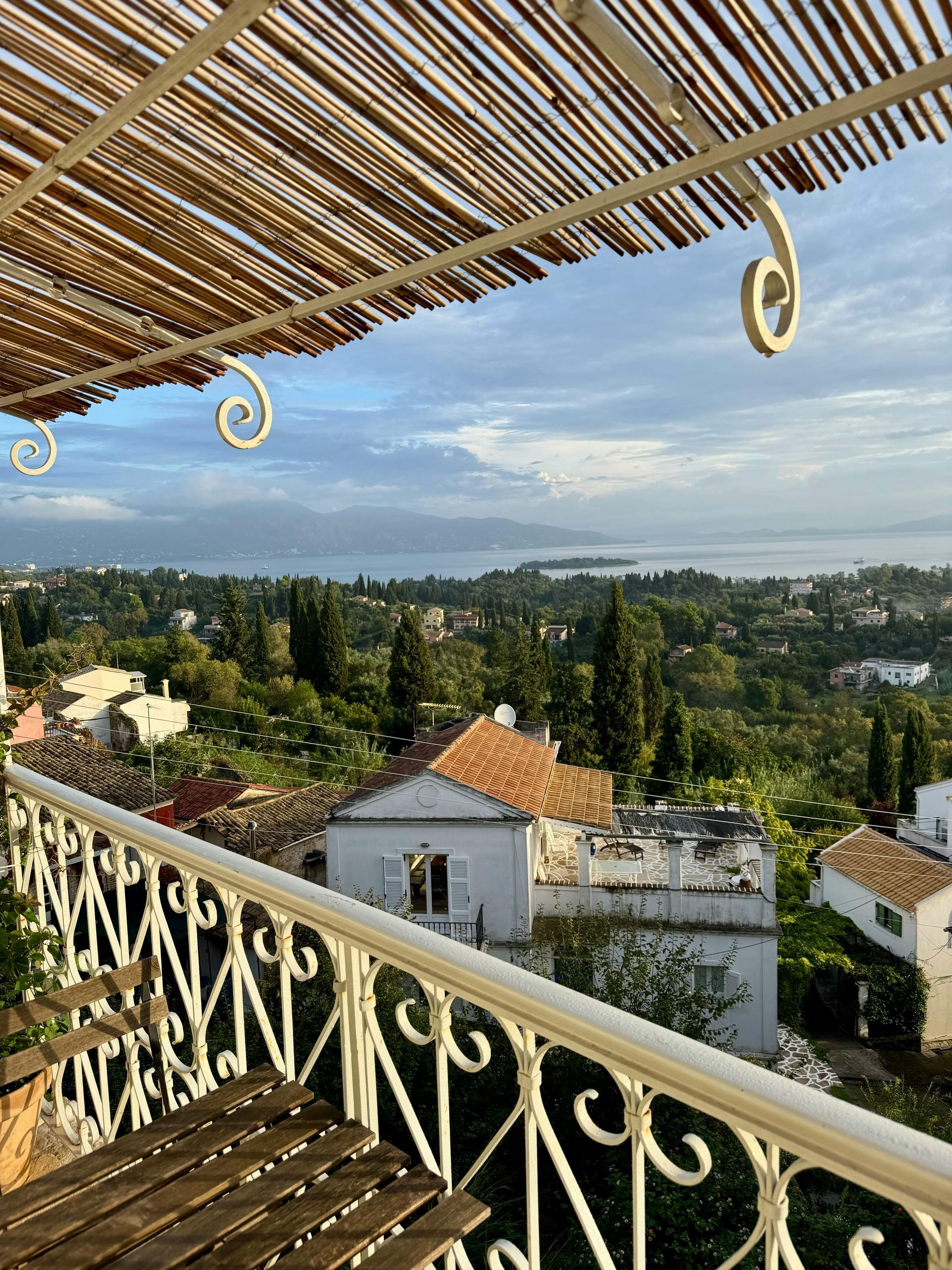 Vedere panoramică a insulei Corfu din Grecia, de la balconul unei vile de vacanță cu acoperiș de stuf.