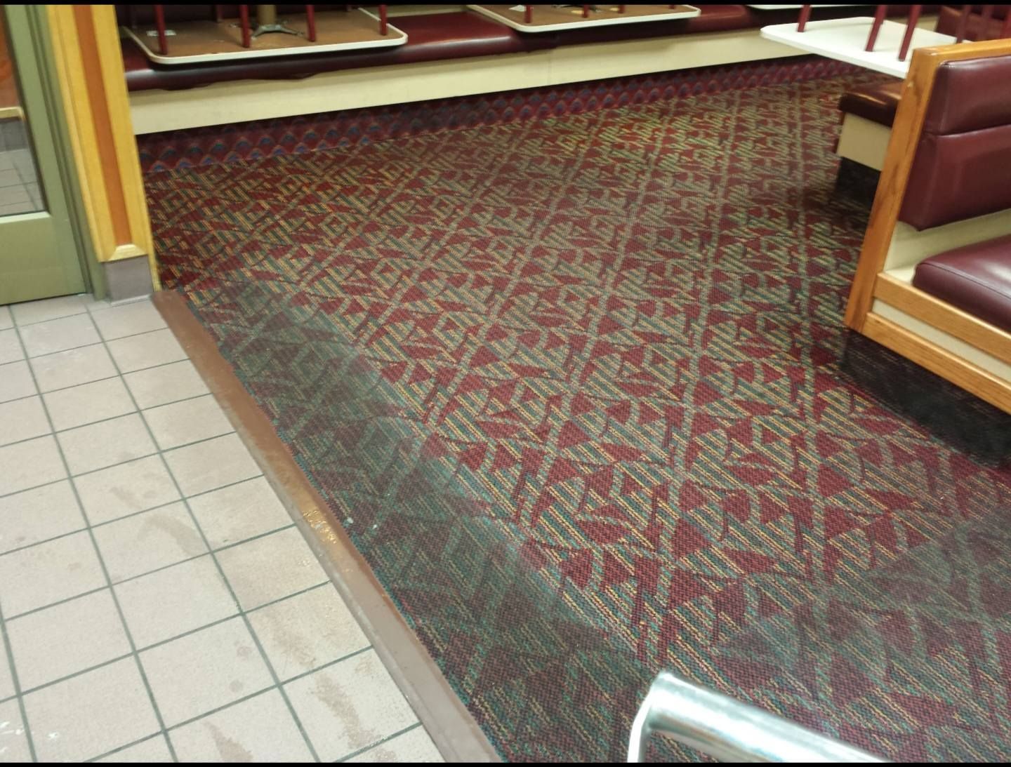 Carpeted seating area with red booths and a tiled floor edge in a restaurant or lobby