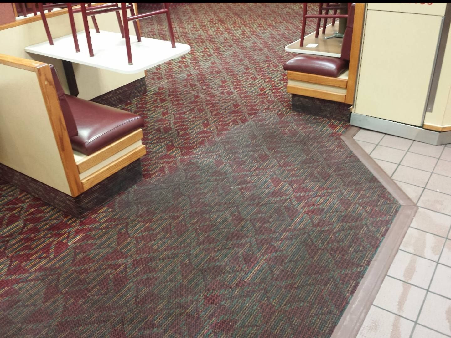 Restaurant booth seating beside a patterned carpet and tiled floor trim