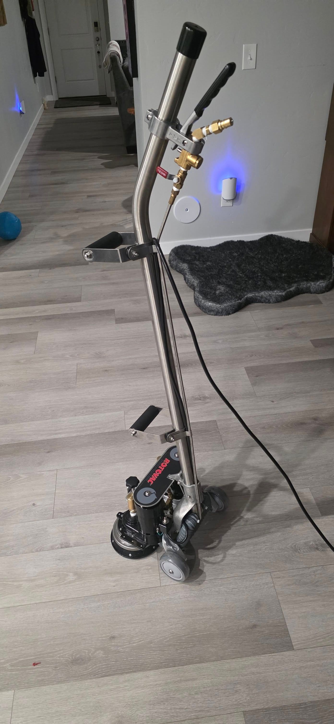 A black scooter or mobility device standing on a wood floor in a hallway, with blue lights visible.