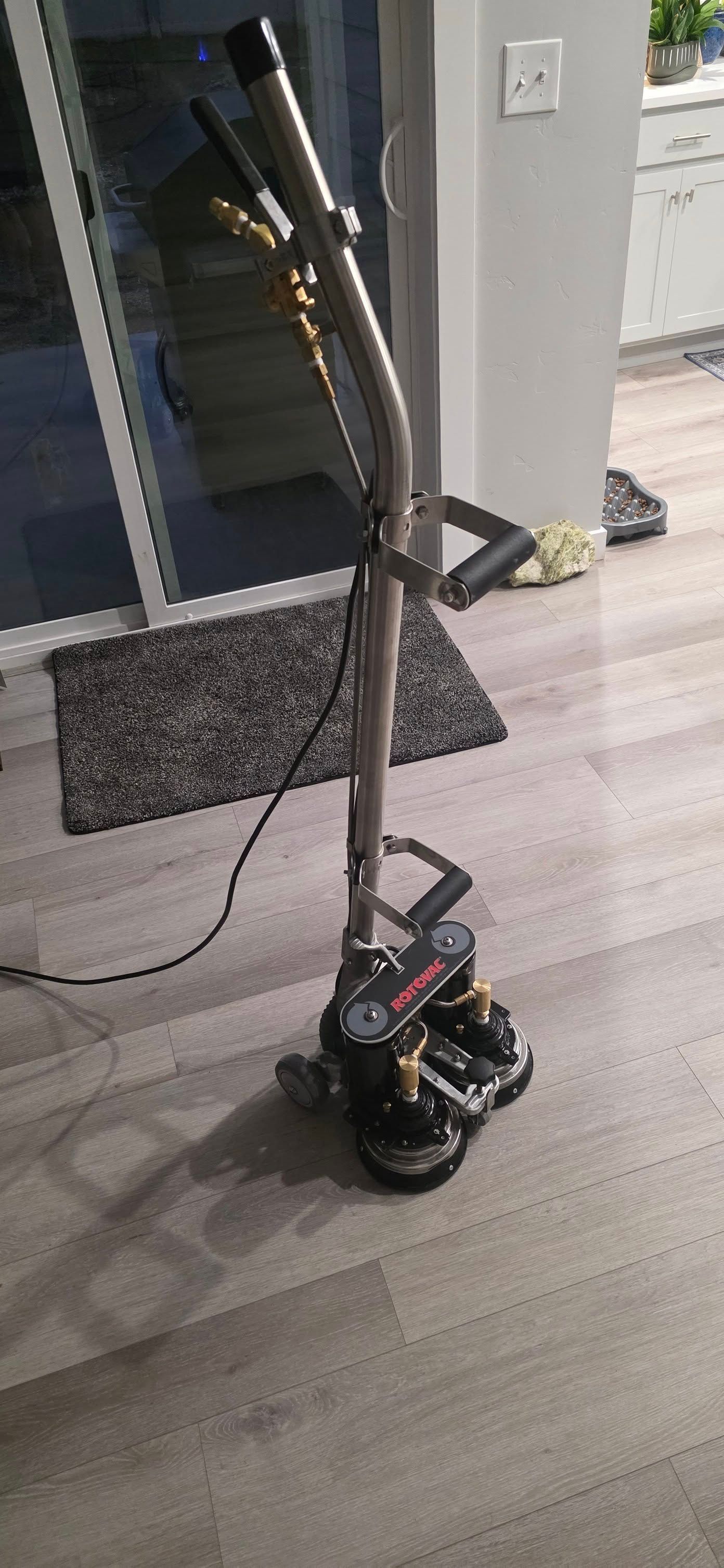A black mobility scooter with a tall handlebar standing on a wooden deck near a doorway.