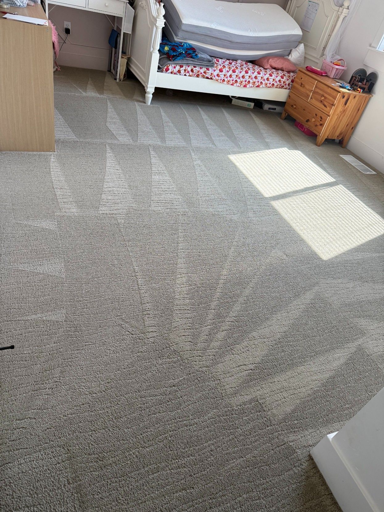 Carpeted bedroom with a bed, dresser, and sunlight patches on the floor.