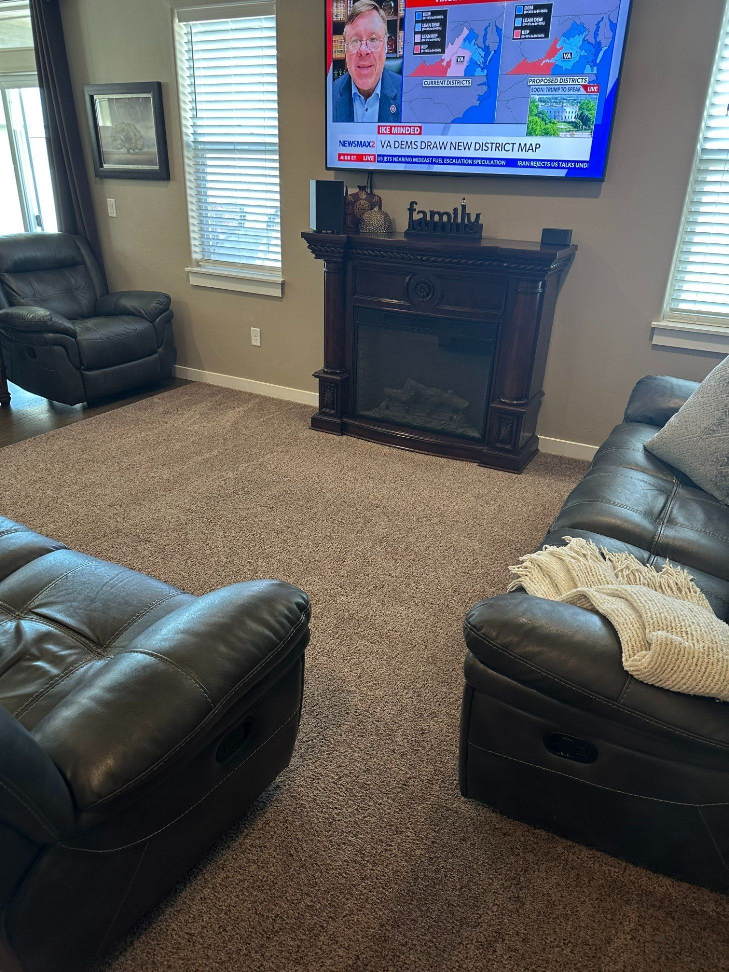 Cozy living room with leather chairs, fireplace, and TV displaying a news broadcast