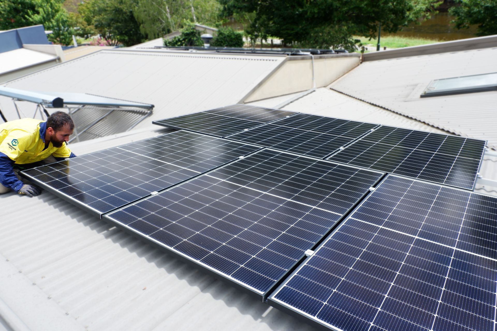 A man is installing solar panels on the roof of a house.