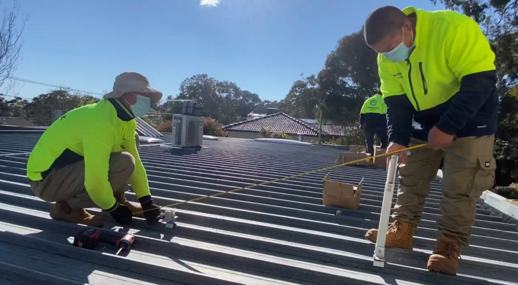 Two men wearing masks are working on a roof.