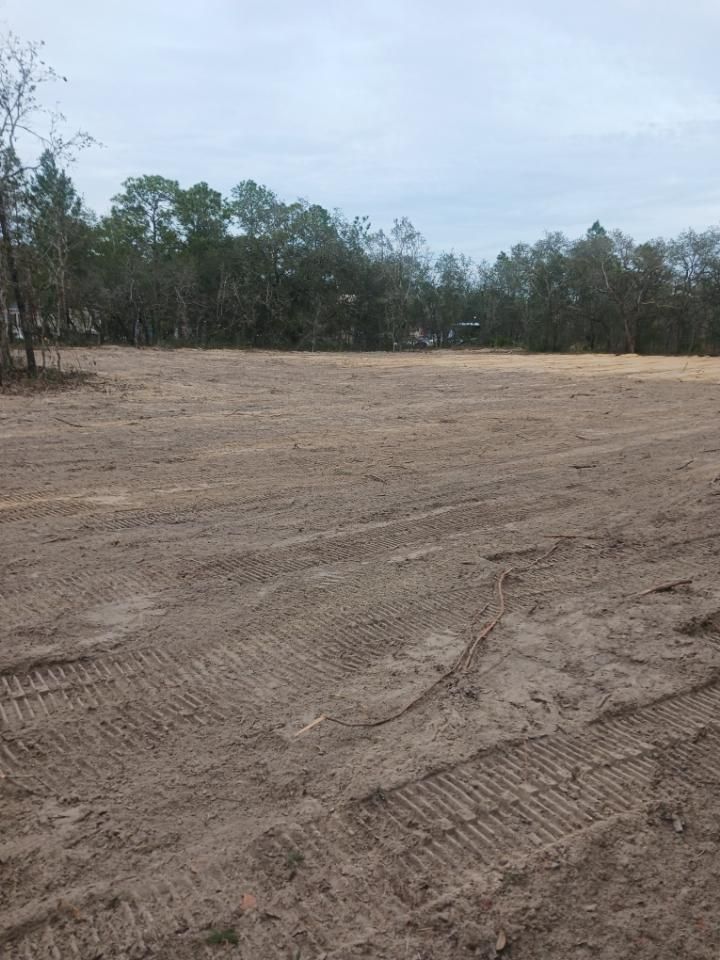 A large dirt field with trees in the background.