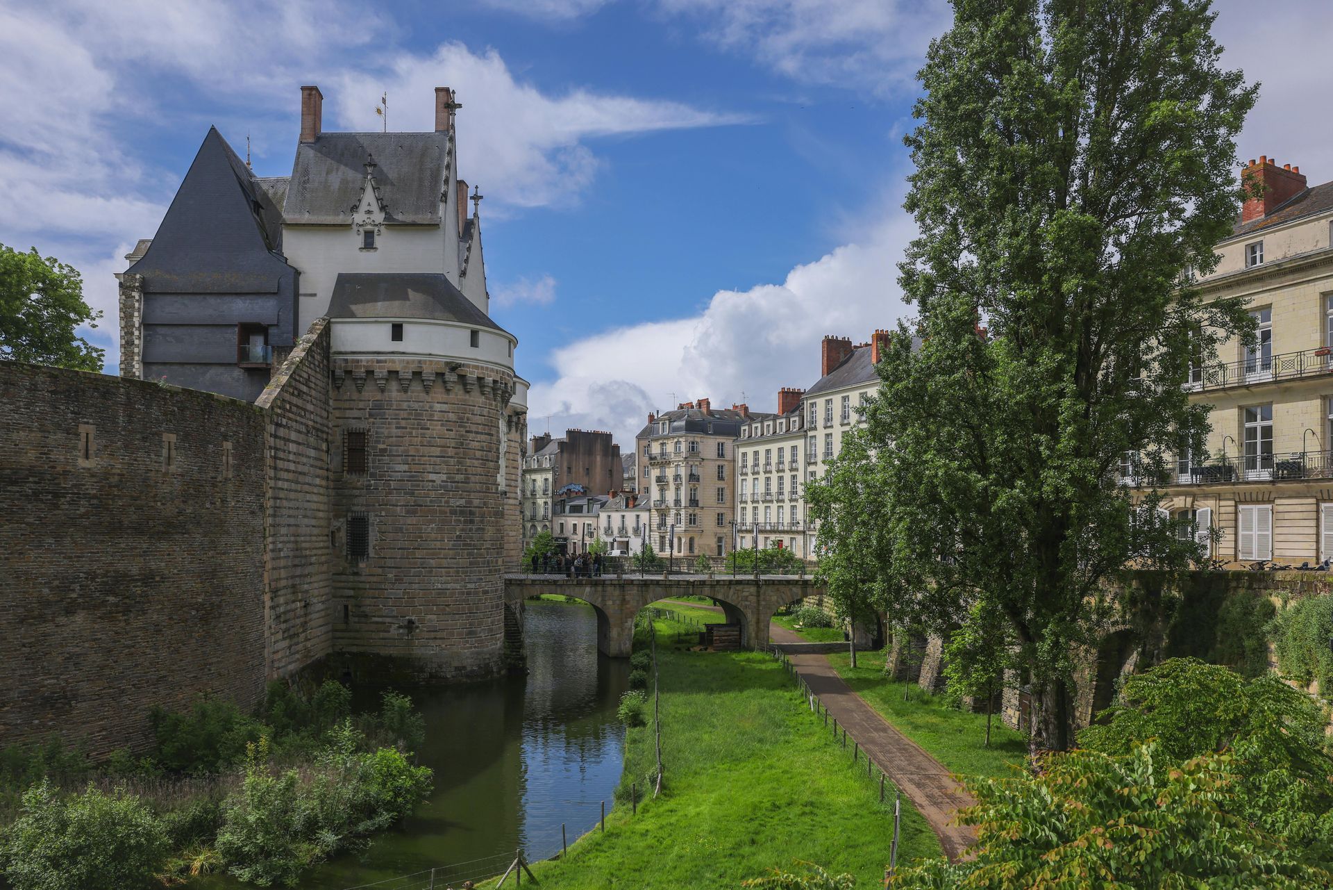 Château et bâtiments le long d'un canal, journée ensoleillée.