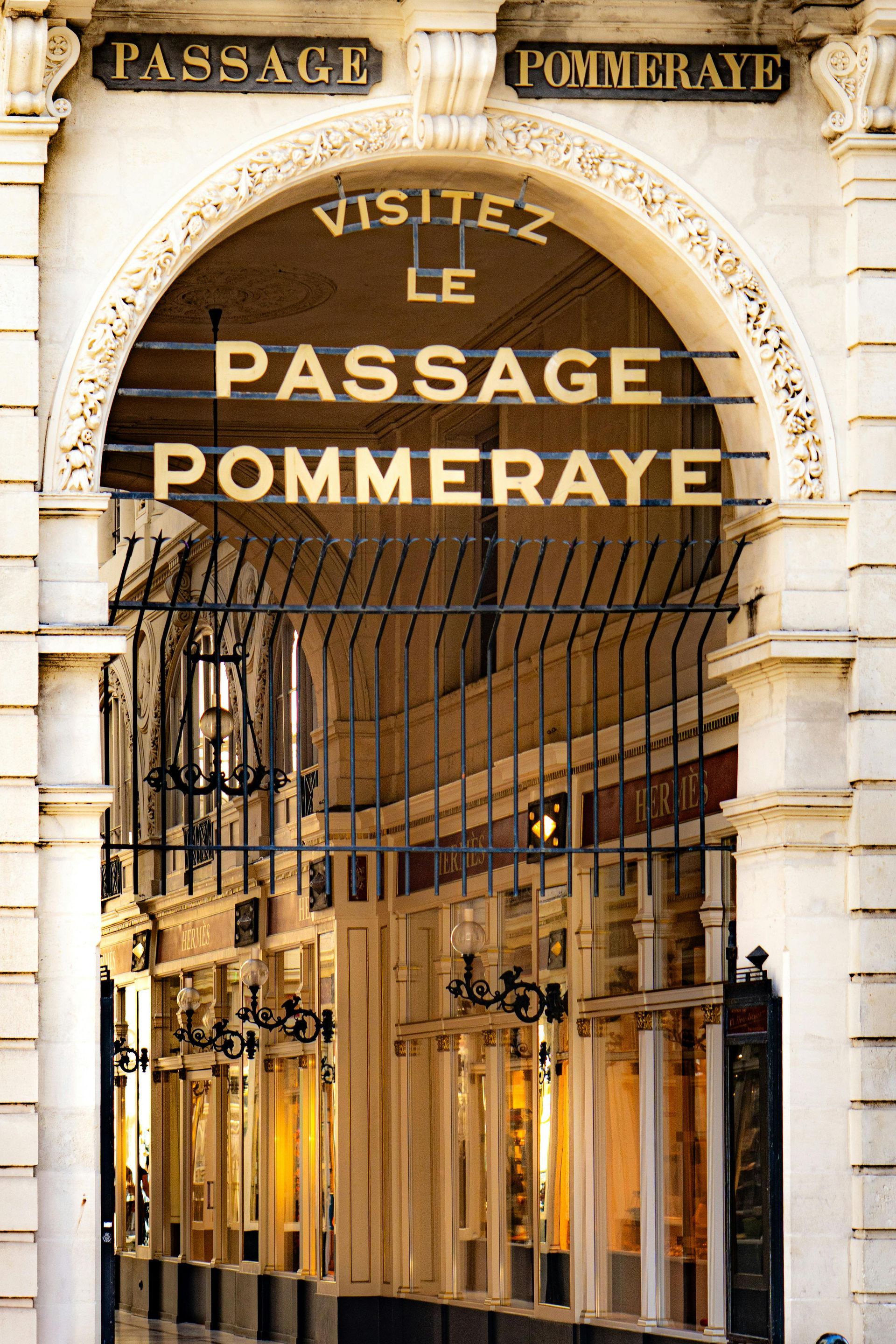 Entrance to Passage Pommeraye, Nantes, France. Beige archway with gold lettering, 