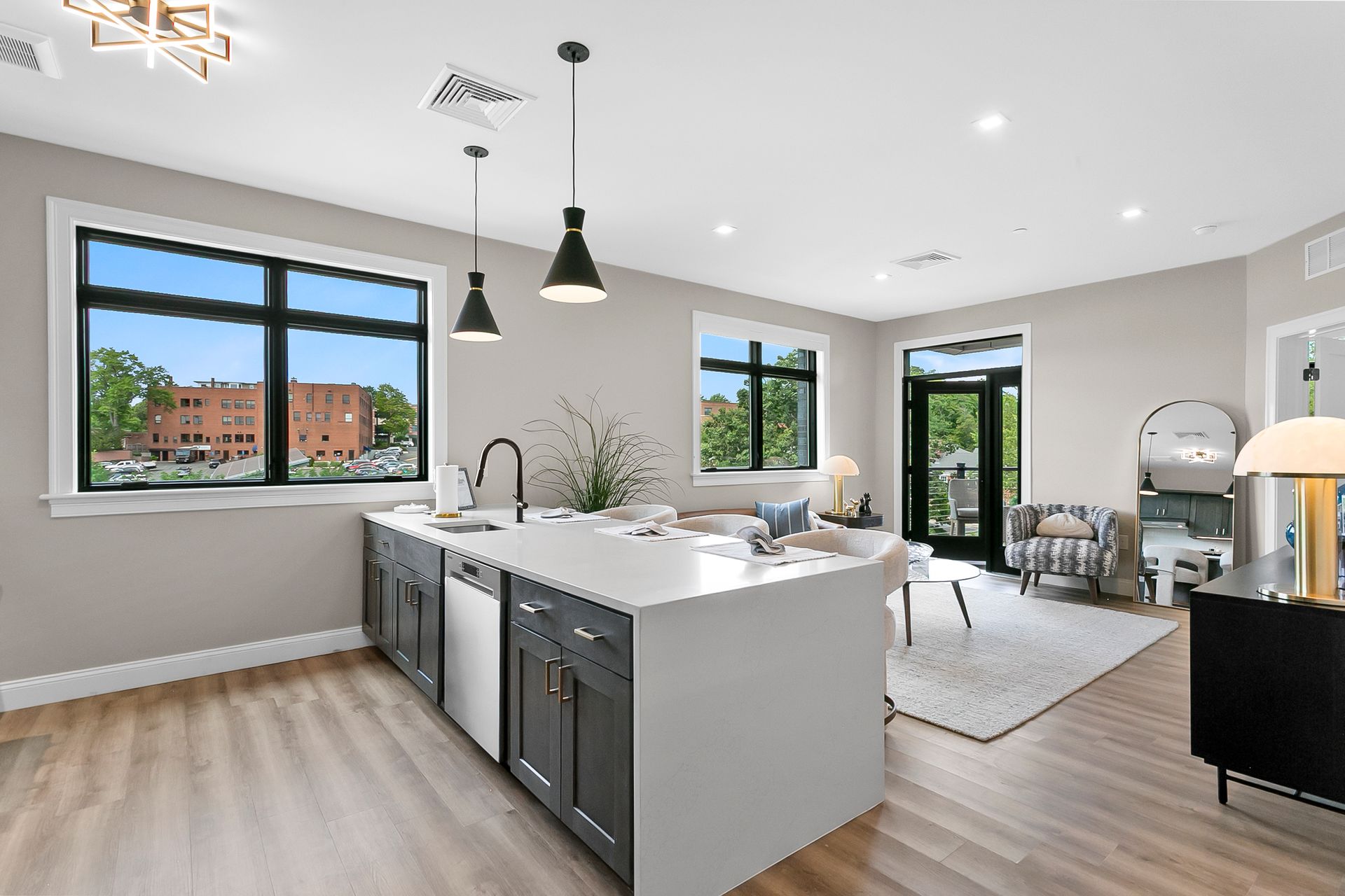 Bright modern open kitchen and living area with island, large windows, and light wood floors
