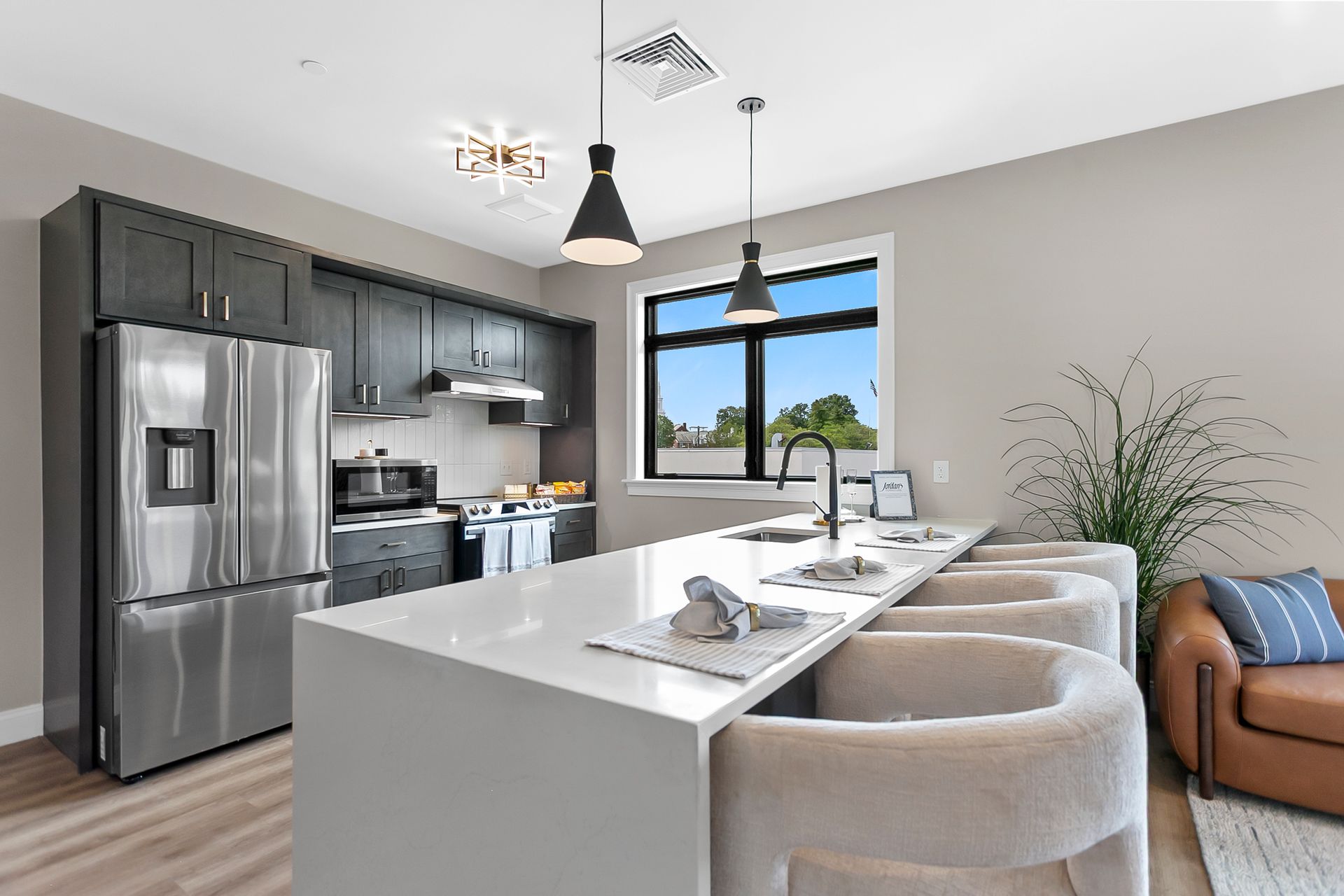 Modern kitchen with stainless appliances, white island seating, and view of the outdoors