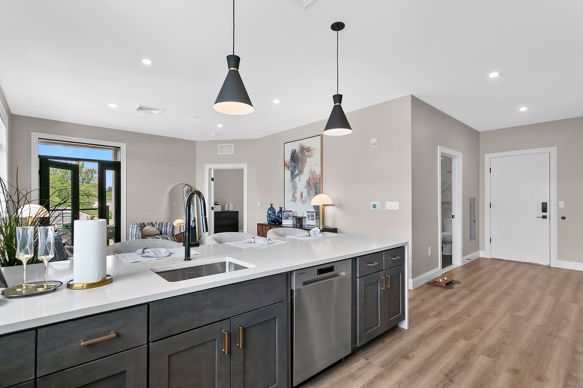Modern kitchen with dark island cabinets, white countertops, pendant lights, and wood flooring