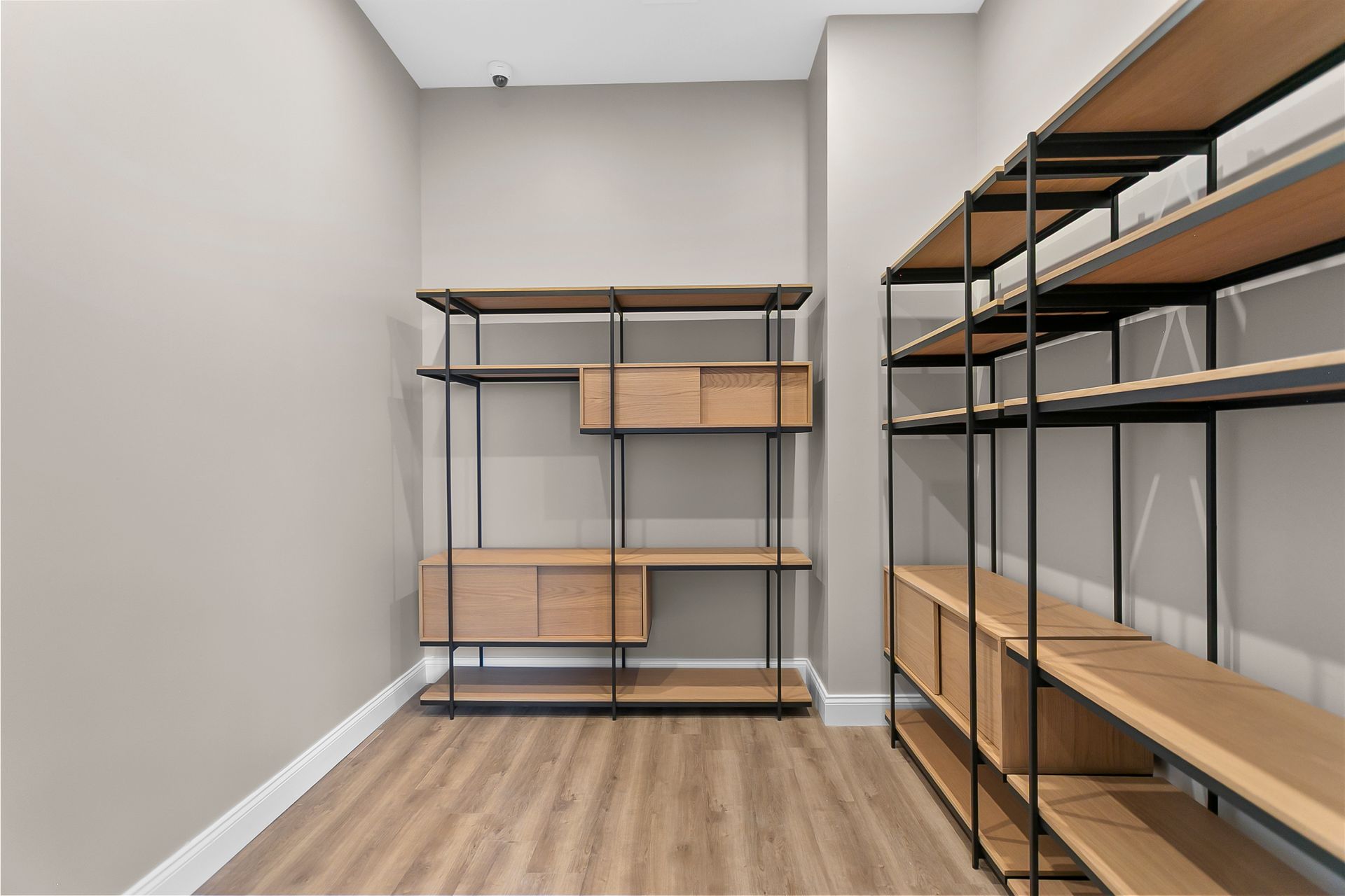 Empty storage room with black metal shelving and cardboard boxes on wood flooring