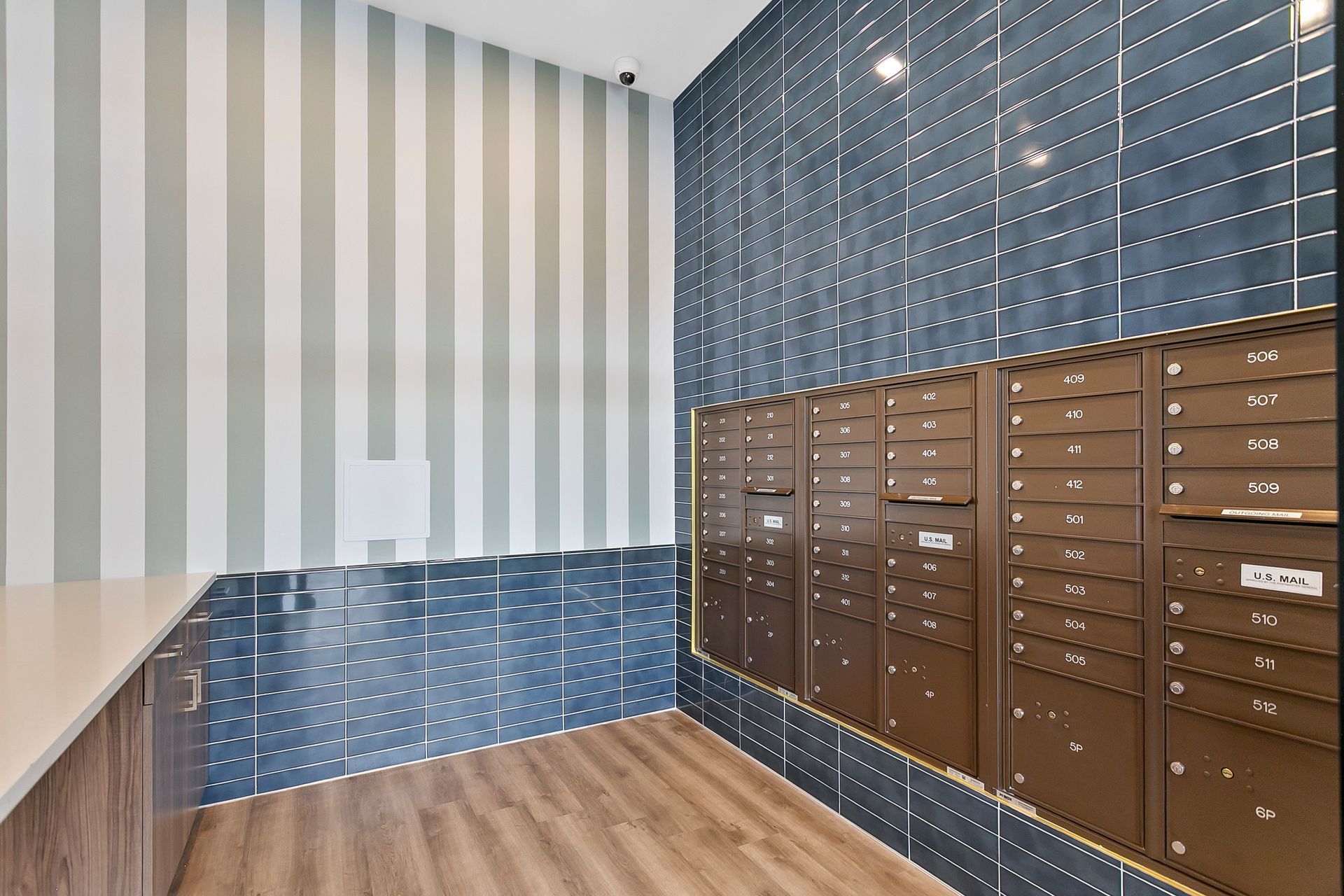 Modern apartment mailroom with blue and brown mailboxes and striped walls