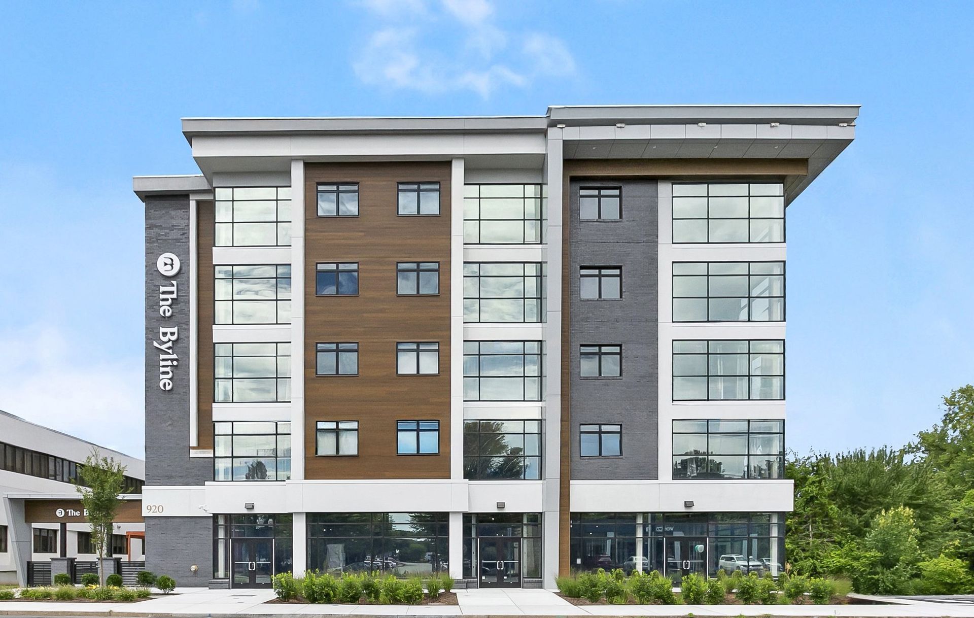 Modern multi-story office building with glass windows and brown facade under a blue sky