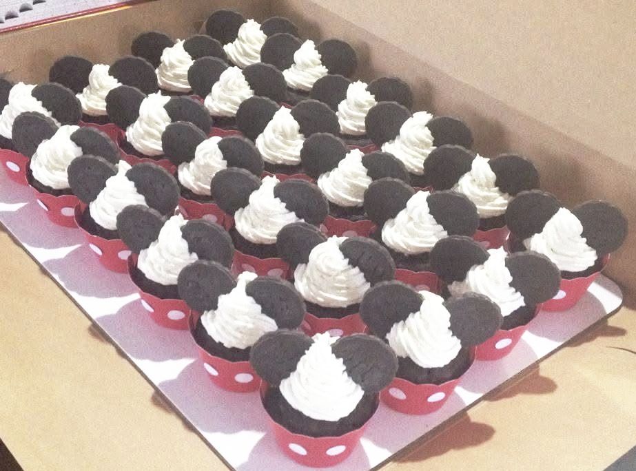 Mickey Mouse cupcakes in red polka dot liners, with white frosting and Oreo ears, arranged in a box.