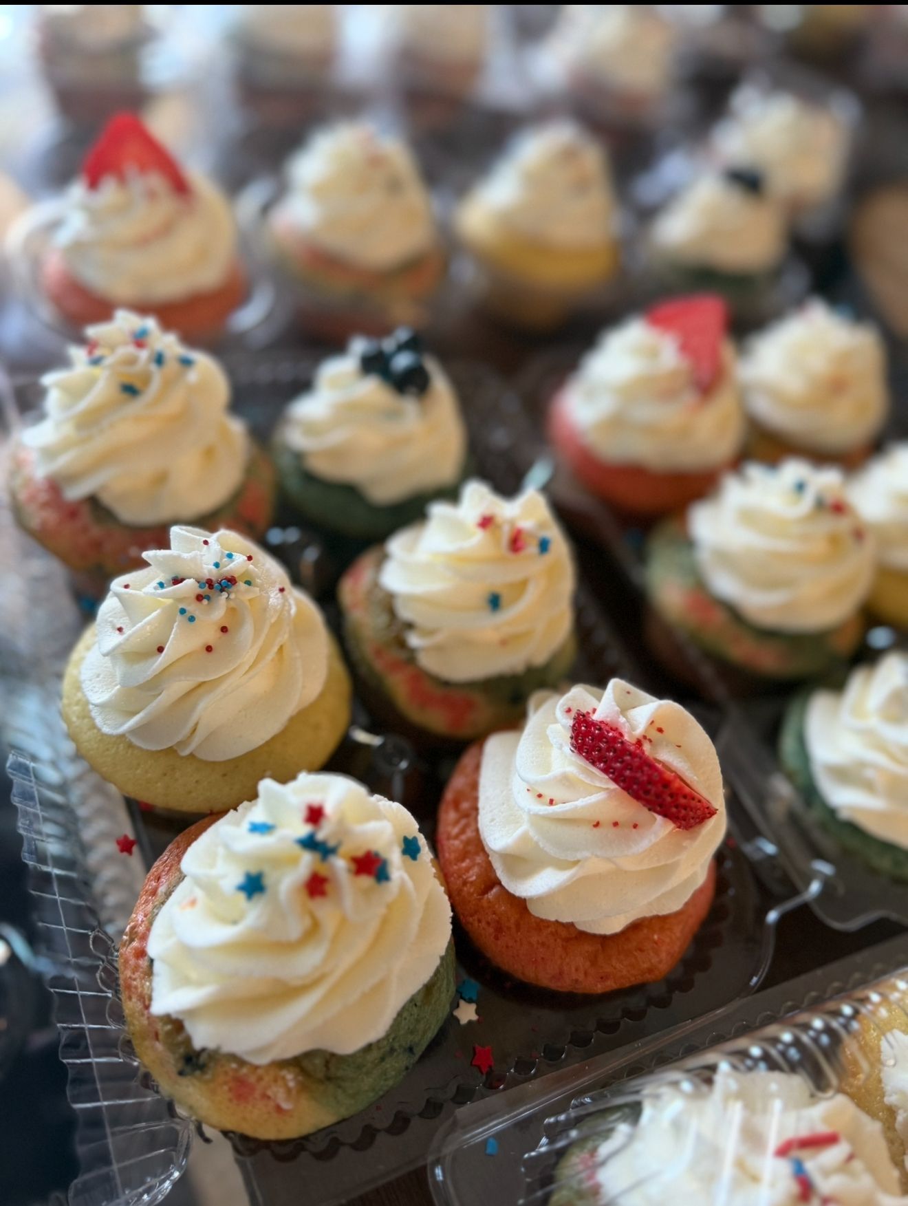 Cupcakes with white frosting and red, white, and blue decorations.