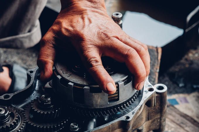 Close-up of a man's hand grabbing a car transmission part
