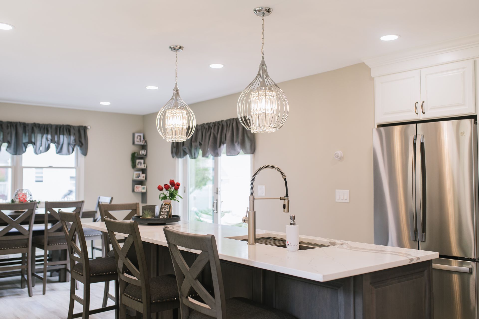 A kitchen with a large island , stainless steel refrigerator , sink and chairs.