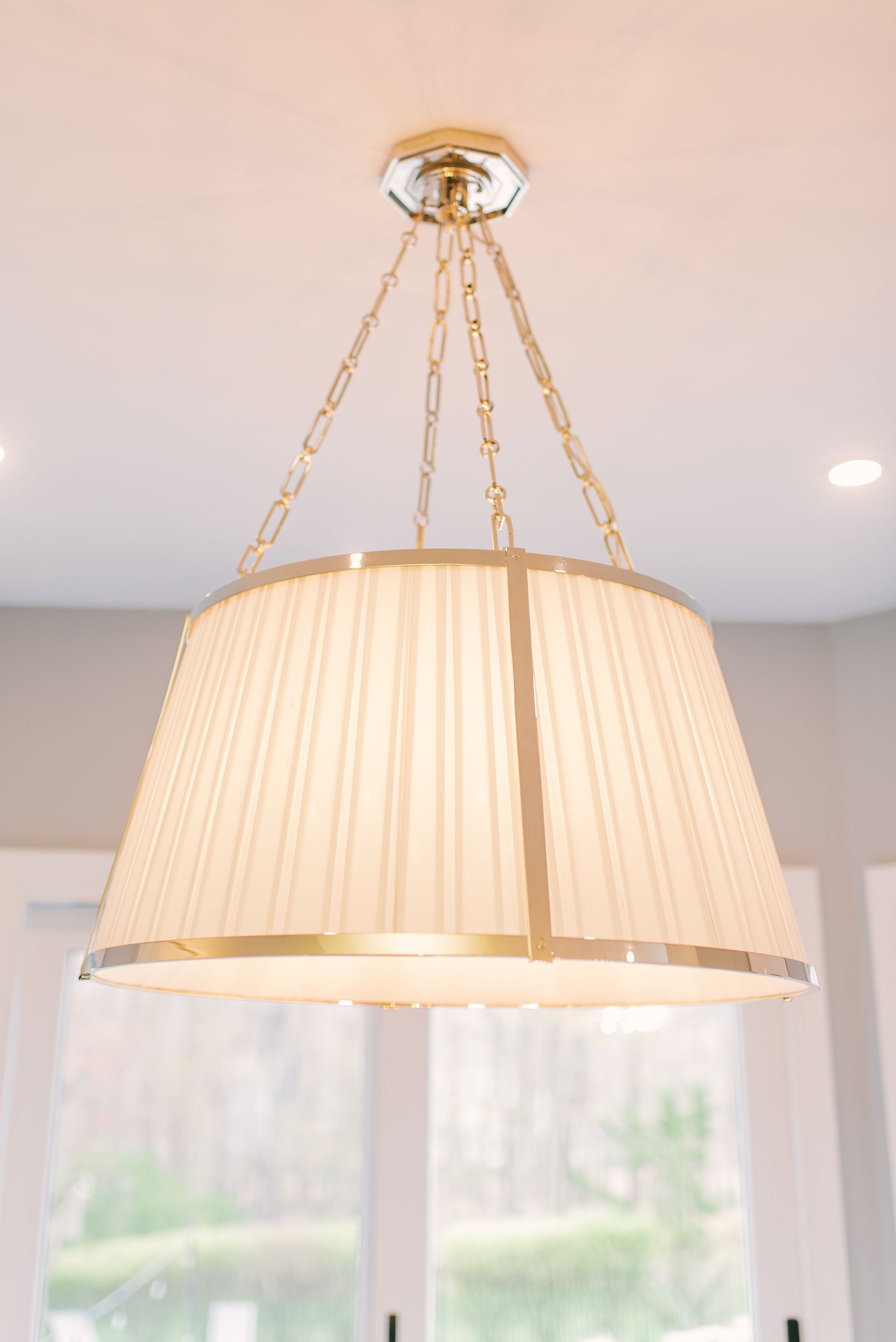 A chandelier with a white shade is hanging from the ceiling in a room.
