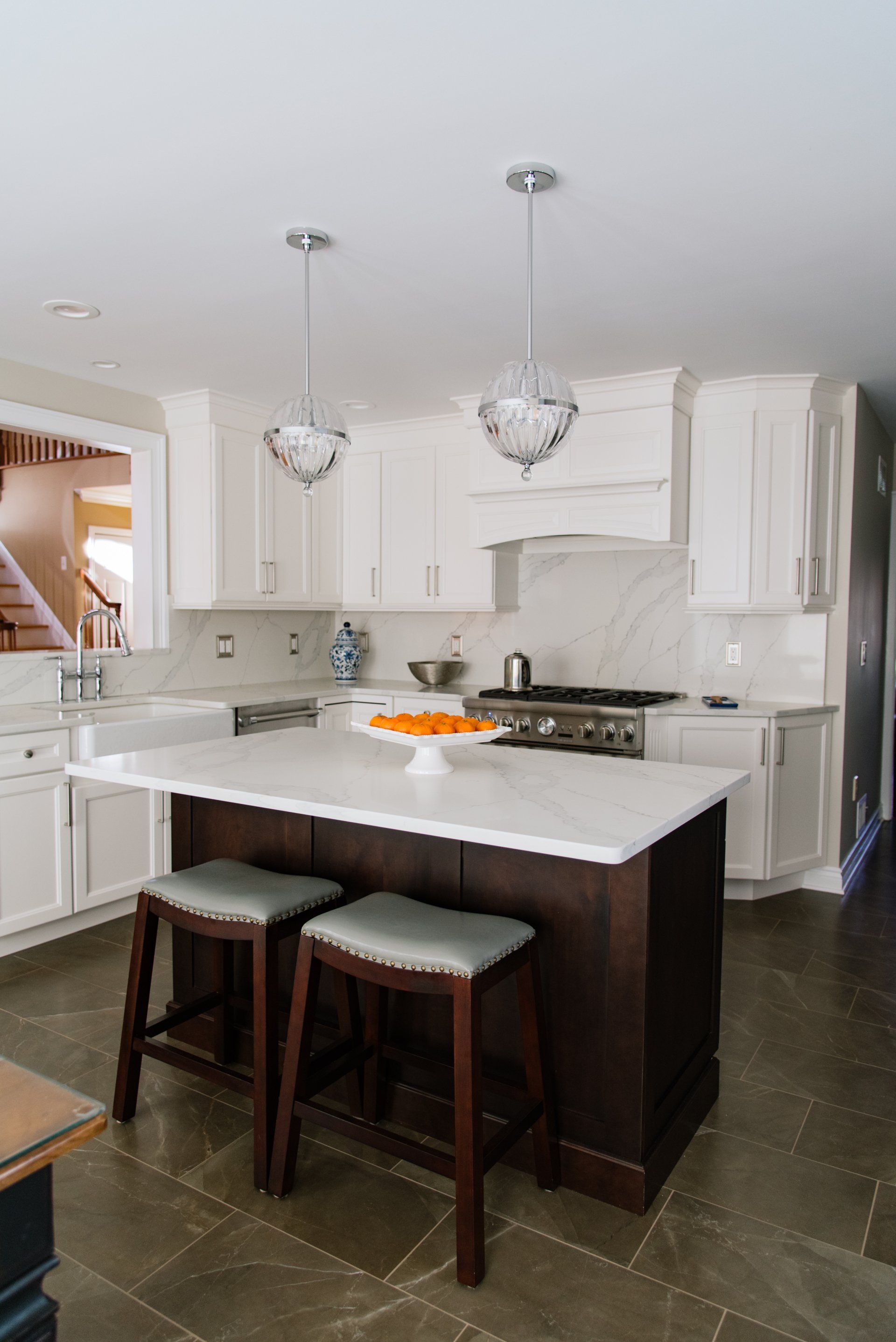 A kitchen with white cabinets and a large island with two stools.