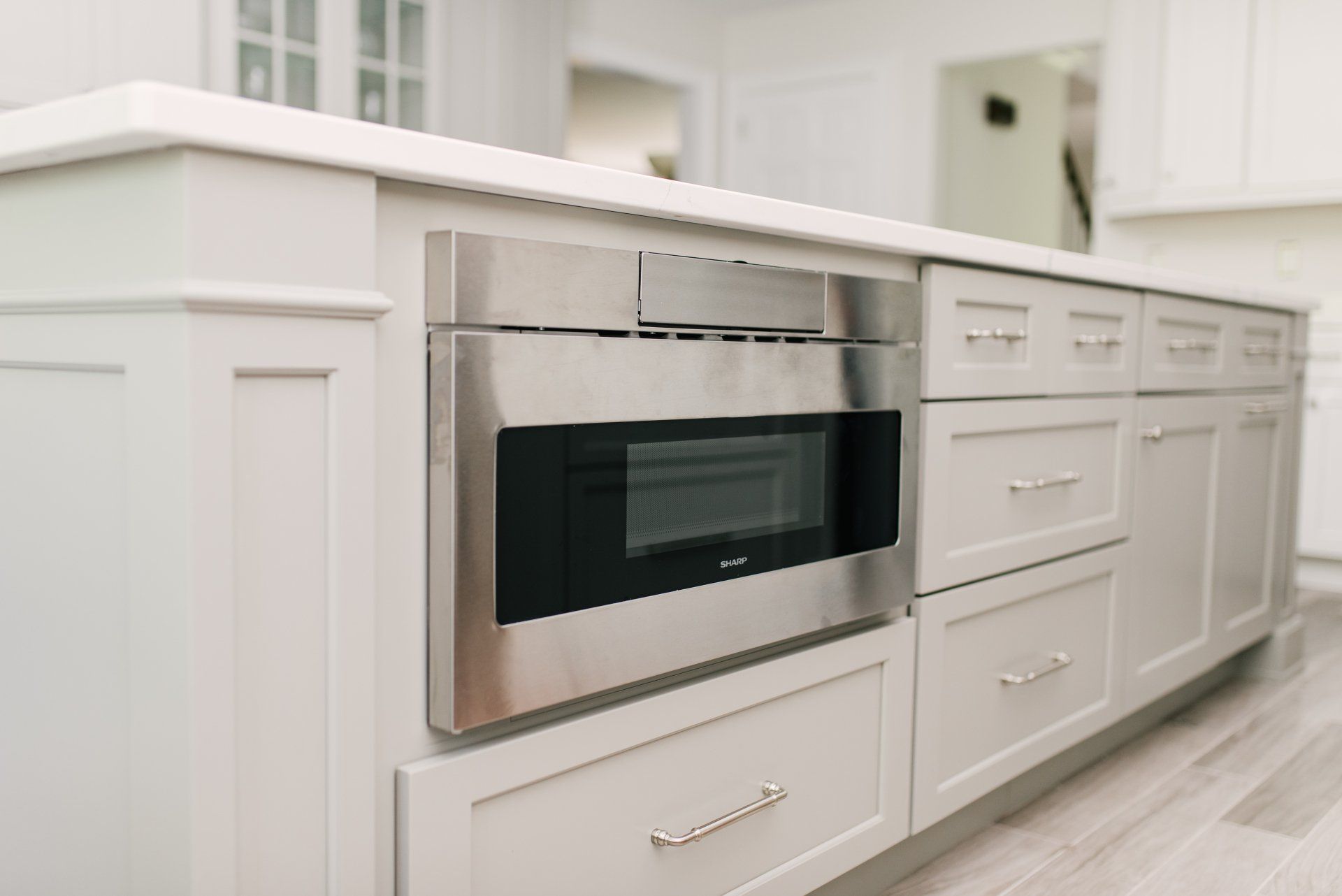 A kitchen with white cabinets and a stainless steel microwave oven.