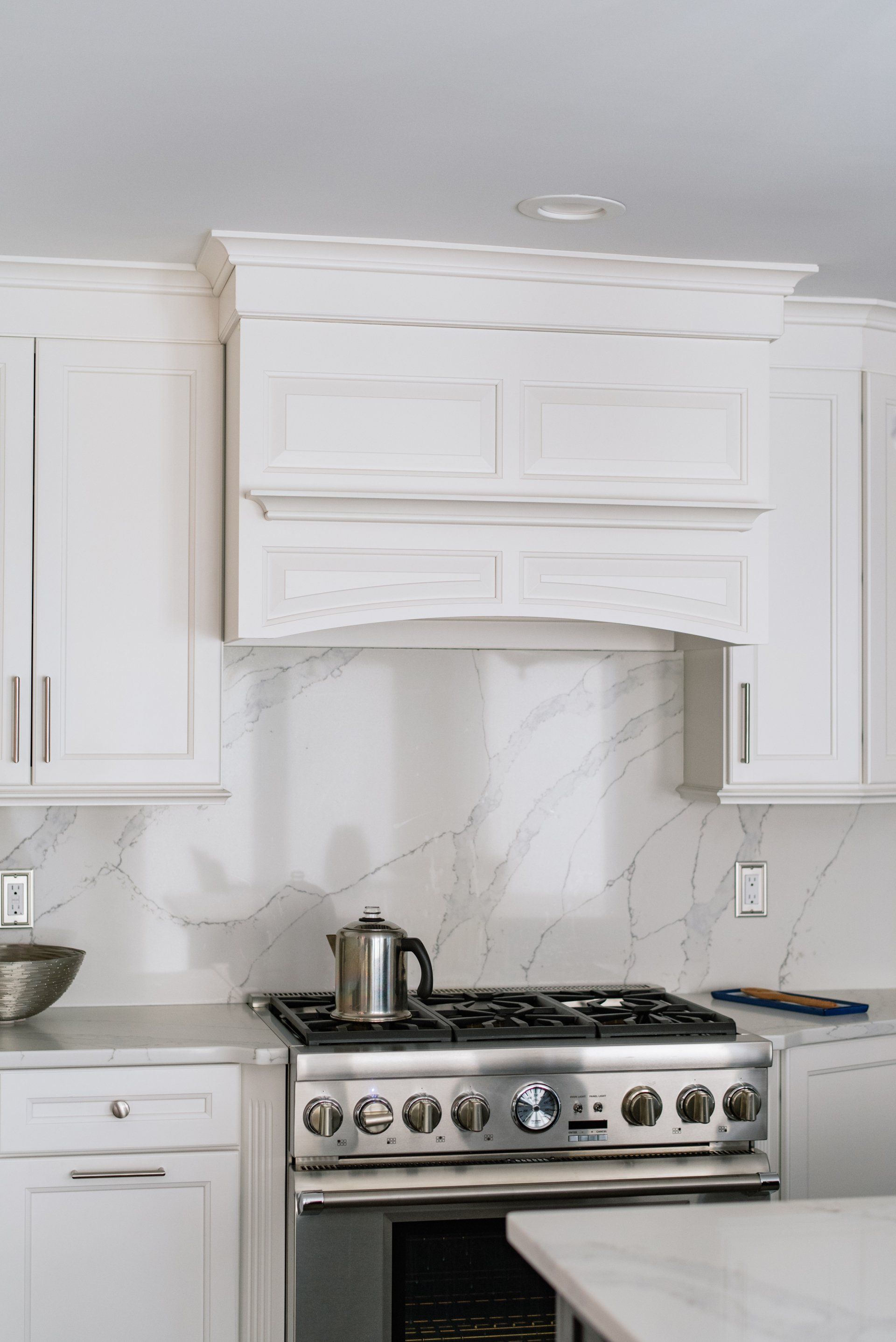 A kitchen with white cabinets and a stove top oven.