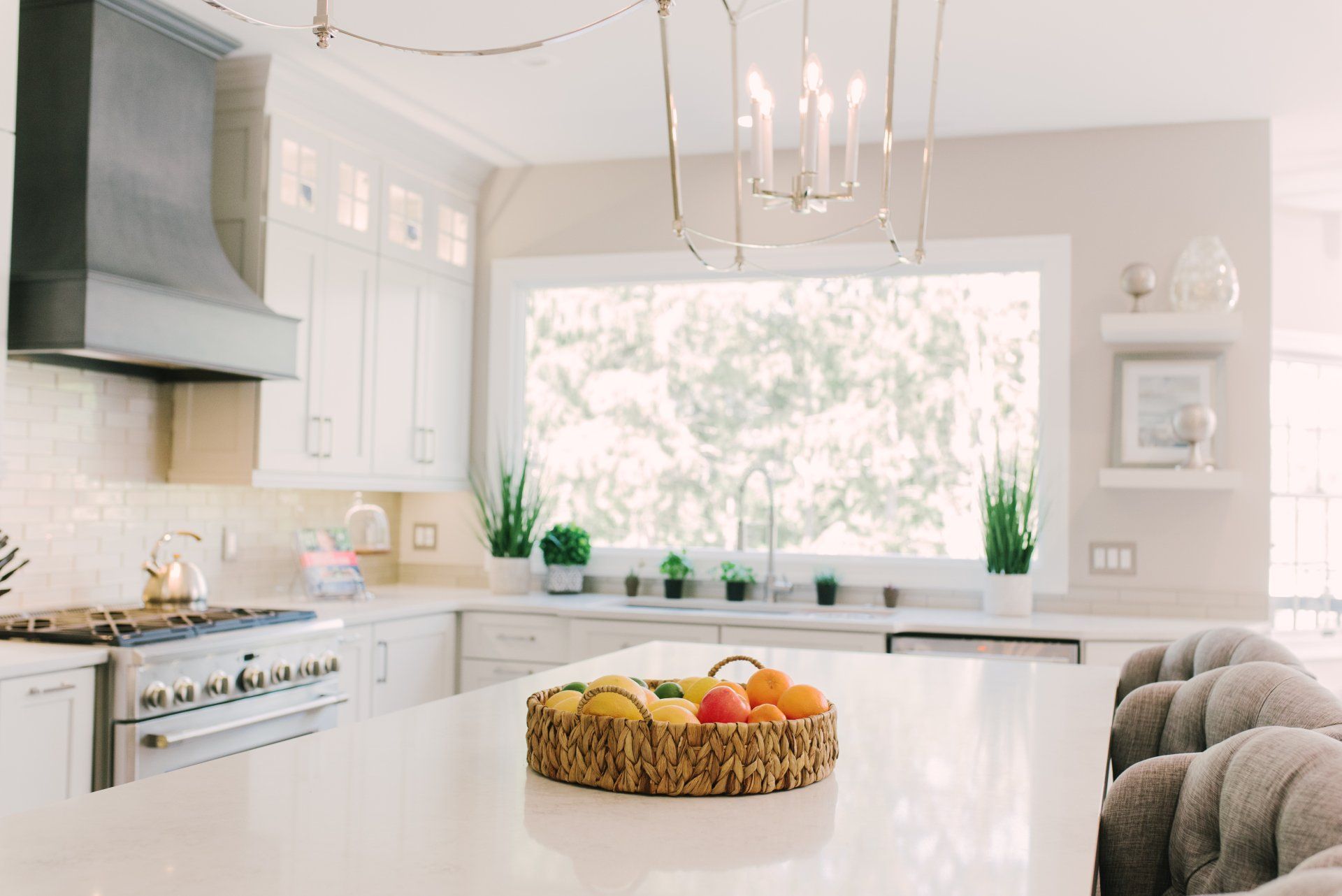 A kitchen with a large window and a bowl of fruit on the counter.