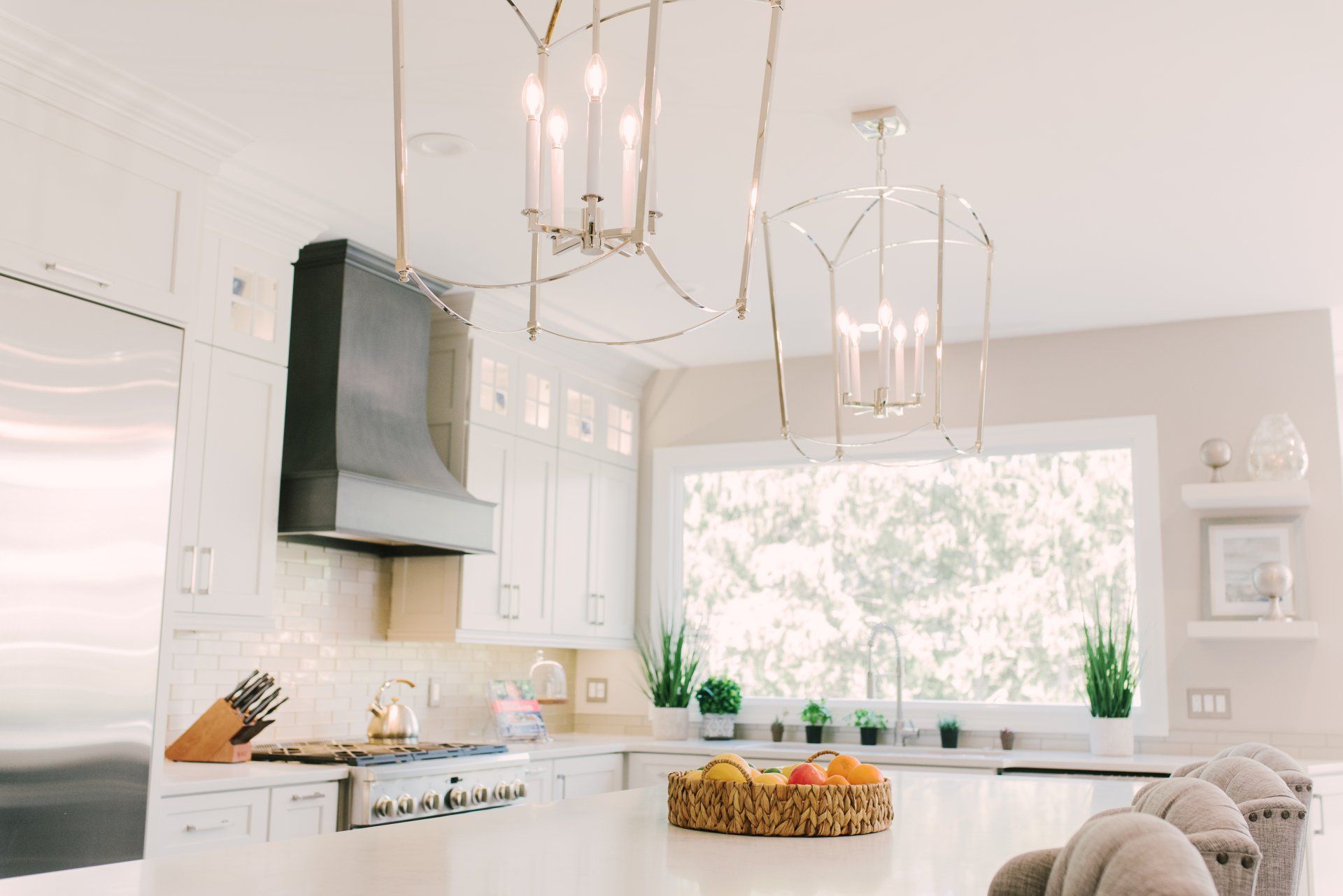 A kitchen with white cabinets , a stove , a sink , and a large window.