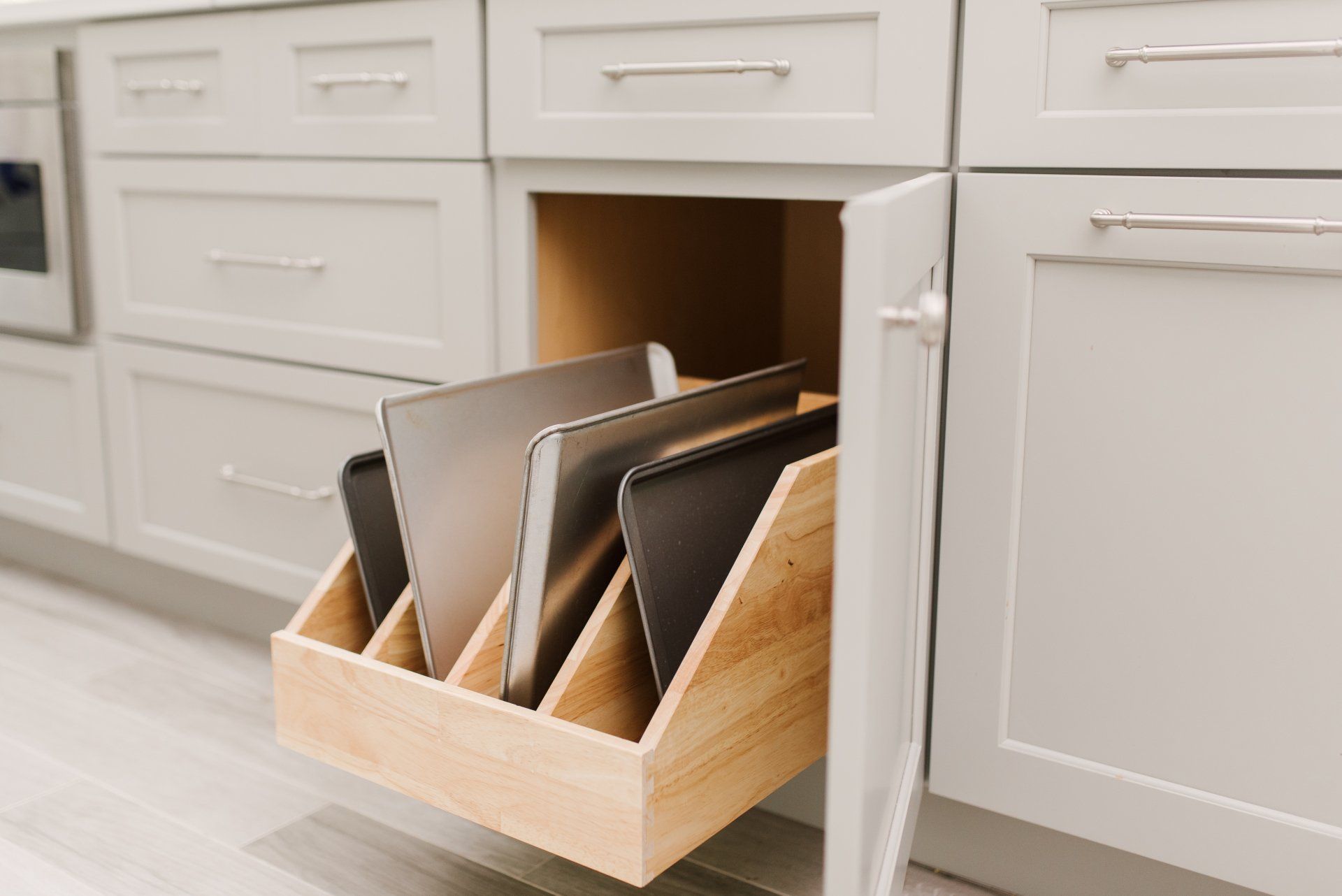 A kitchen cabinet with a wooden drawer filled with laptops.