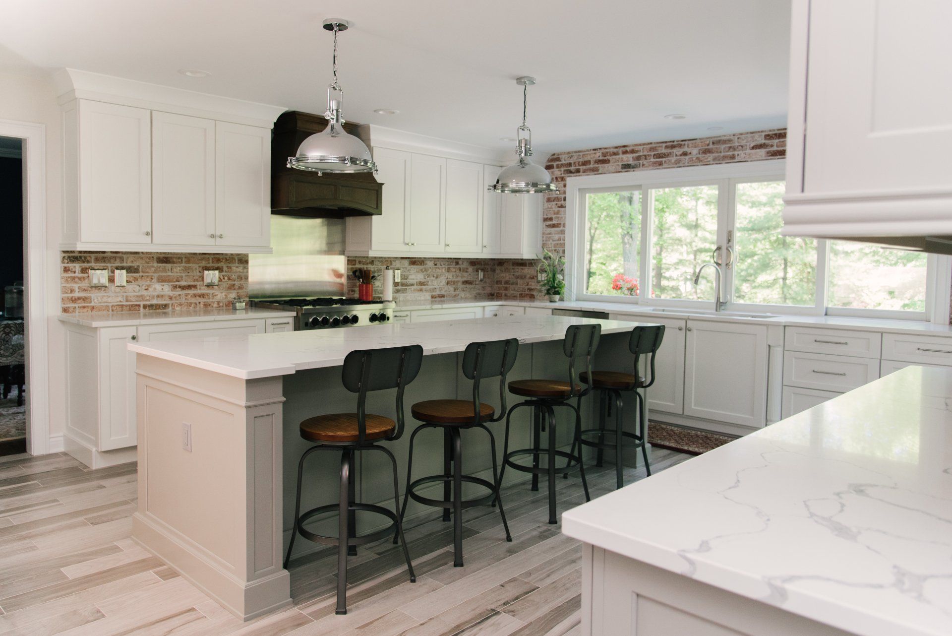 A kitchen with white cabinets and a large island with stools.