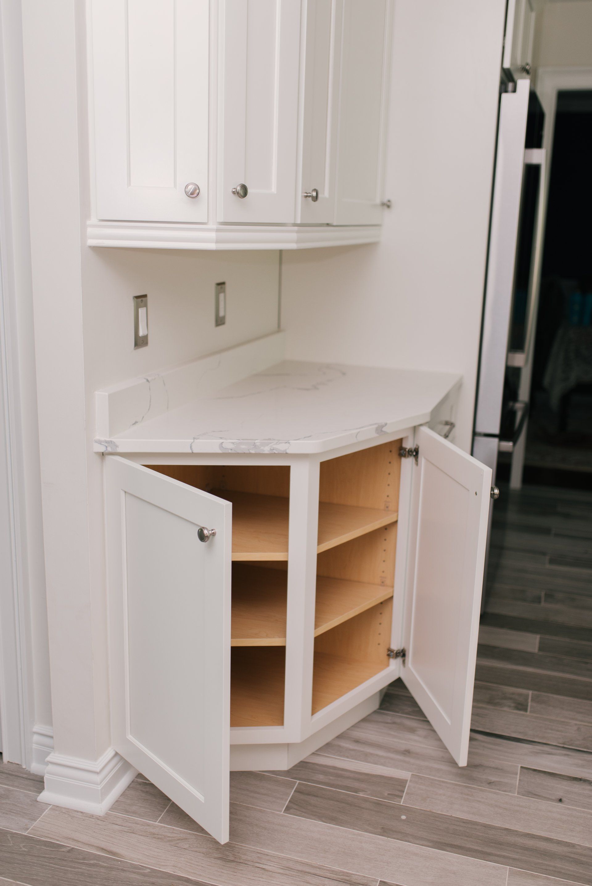 A kitchen cabinet with the doors open and shelves.