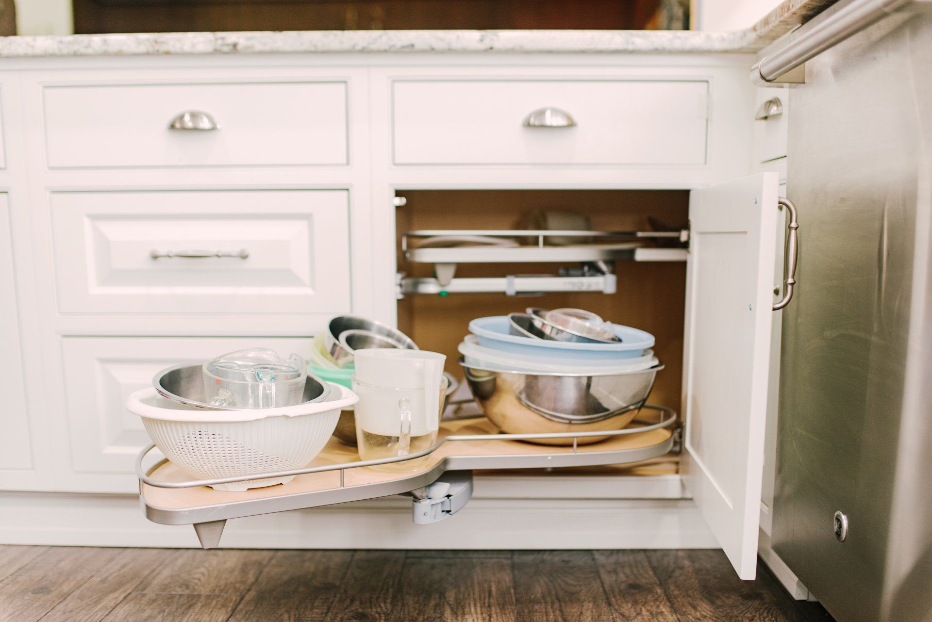 A kitchen cabinet with a sliding shelf filled with pots and pans.