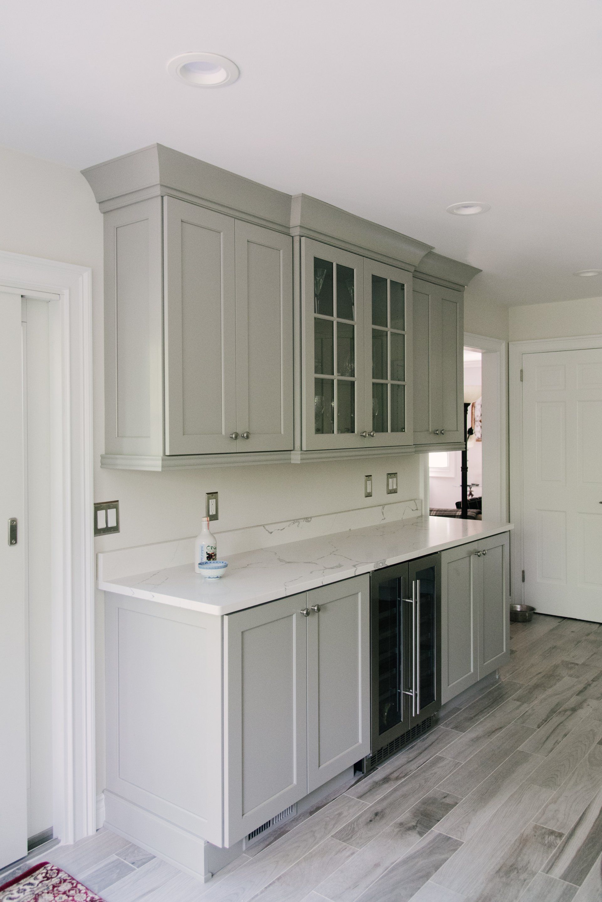 A kitchen with gray cabinets and white counter tops