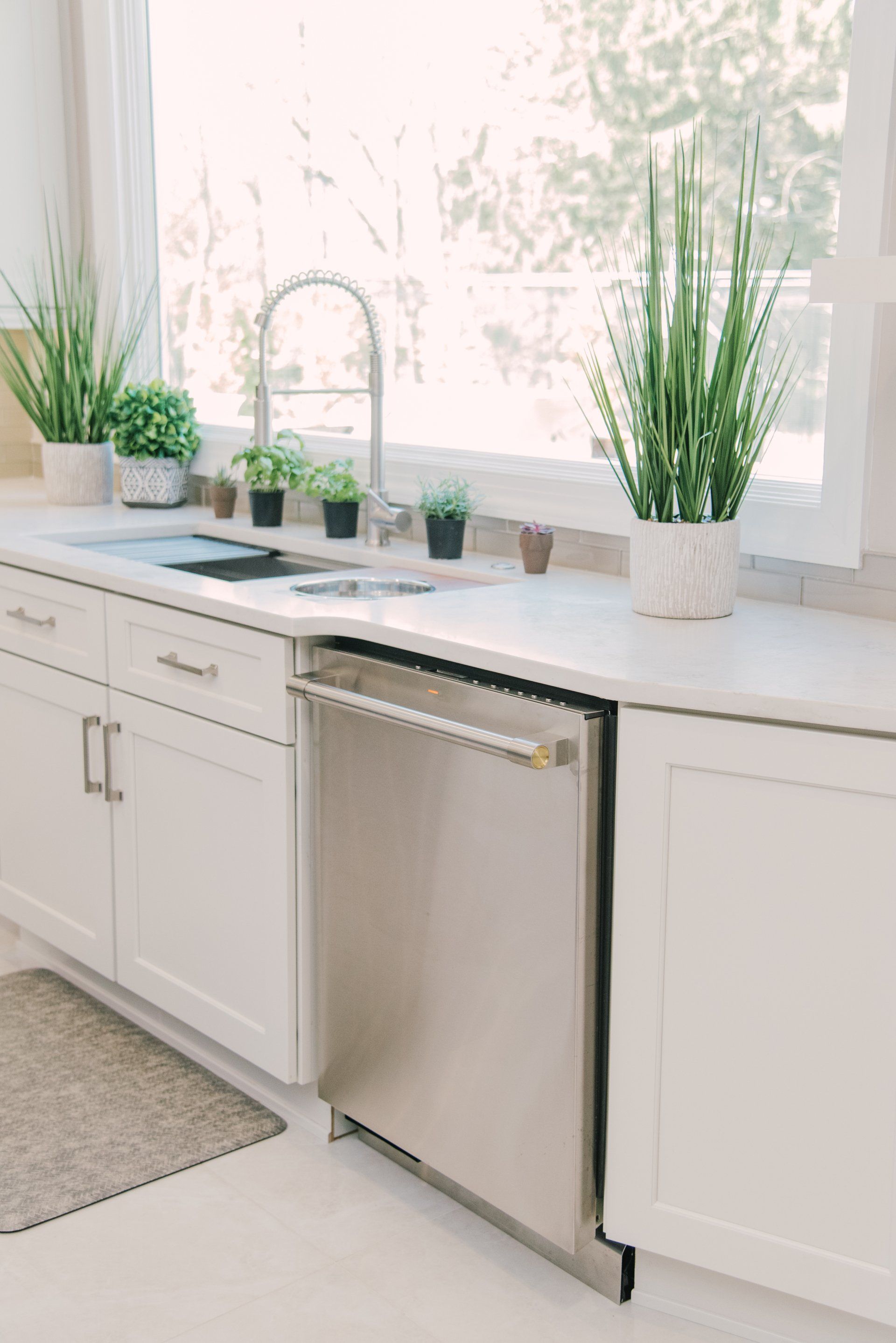 A kitchen with white cabinets and a stainless steel dishwasher.