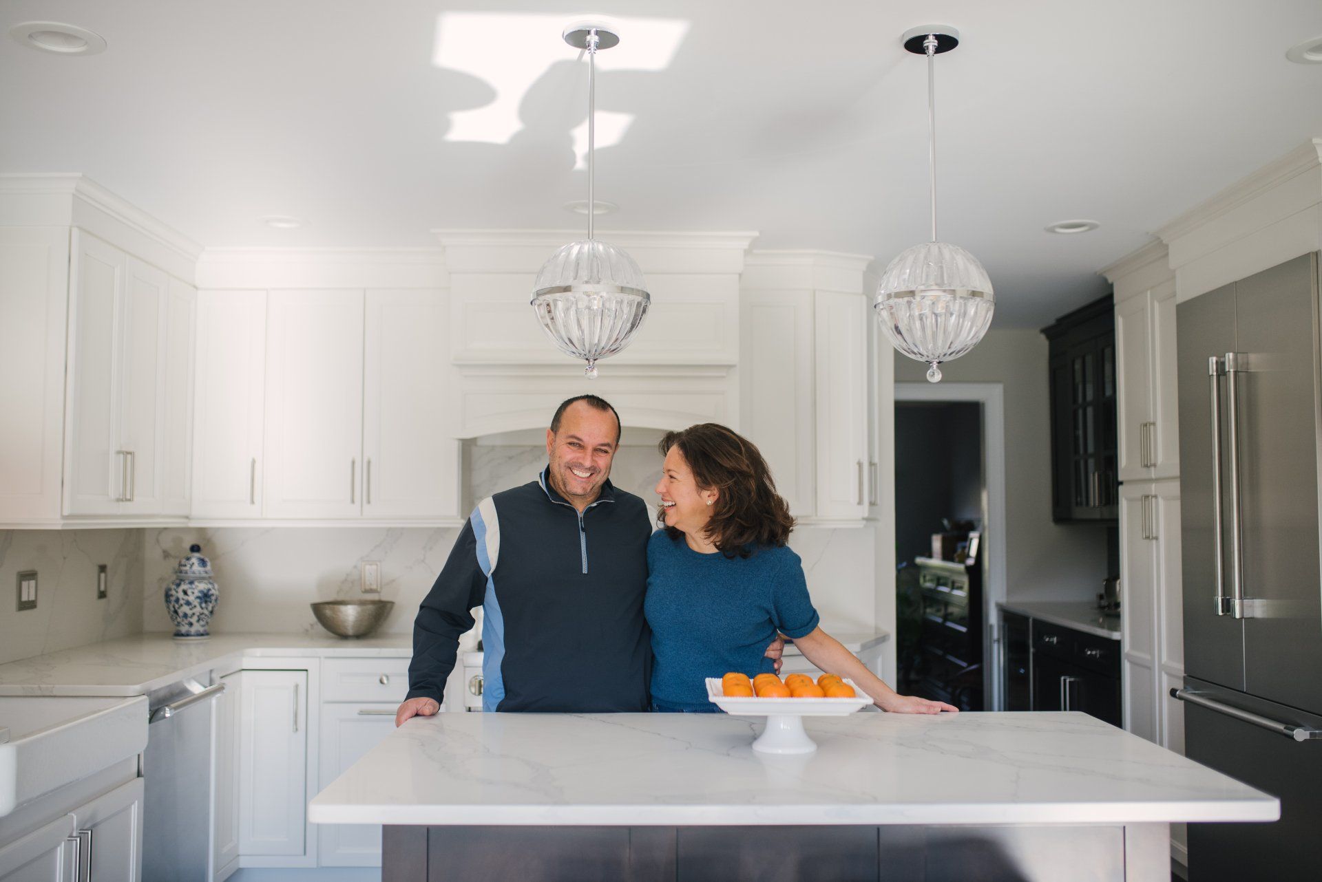 A man and a woman are standing next to each other in a kitchen.