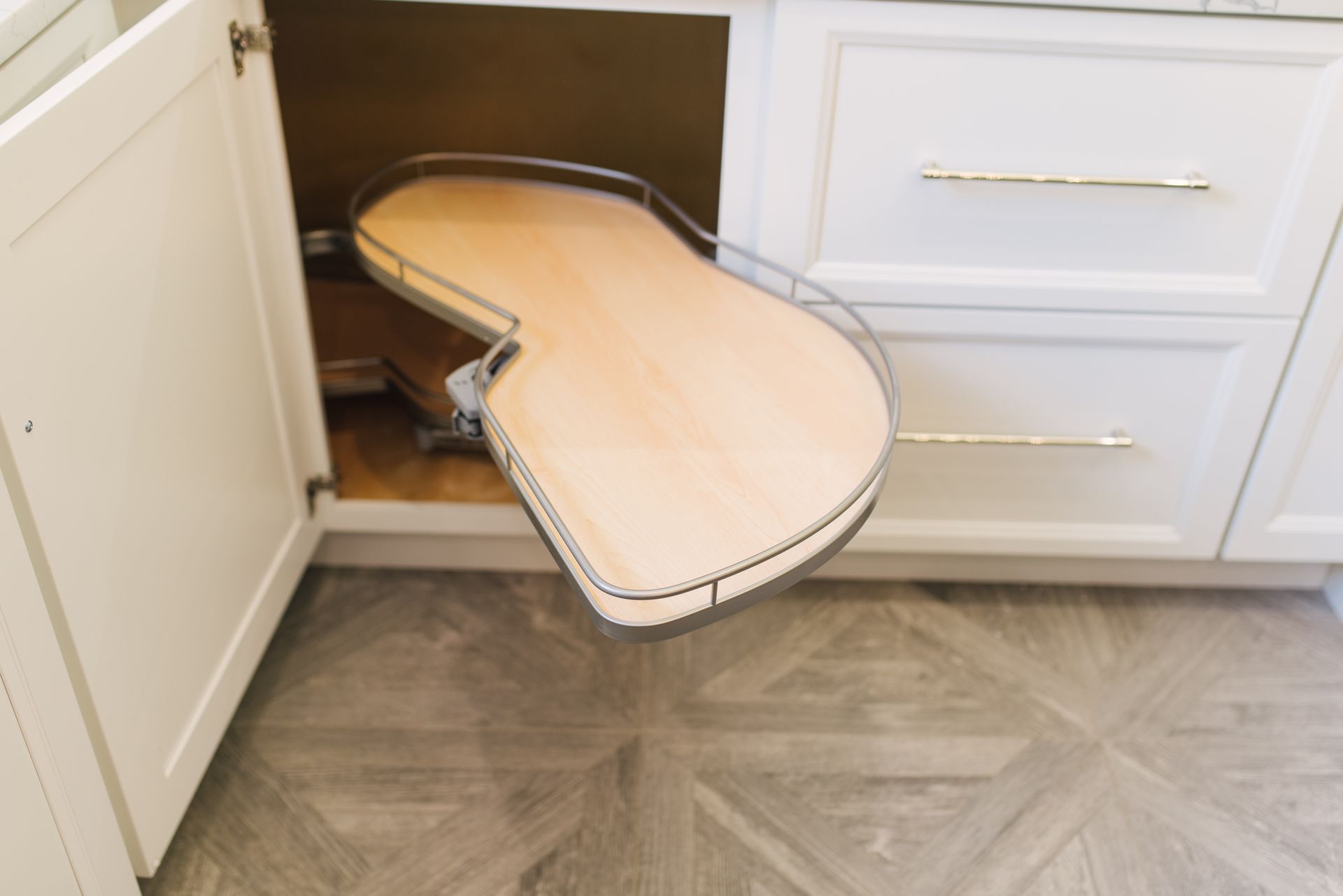 A kitchen cabinet with a wooden tray pulled out of it.