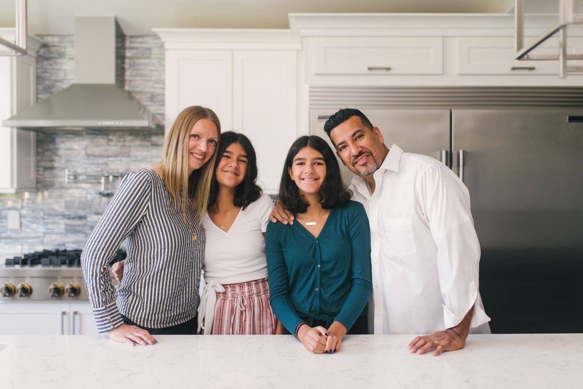 A family is posing for a picture in a kitchen.