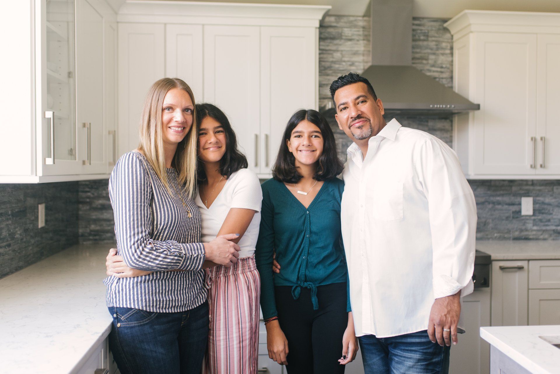 A family is posing for a picture in their new kitchen.