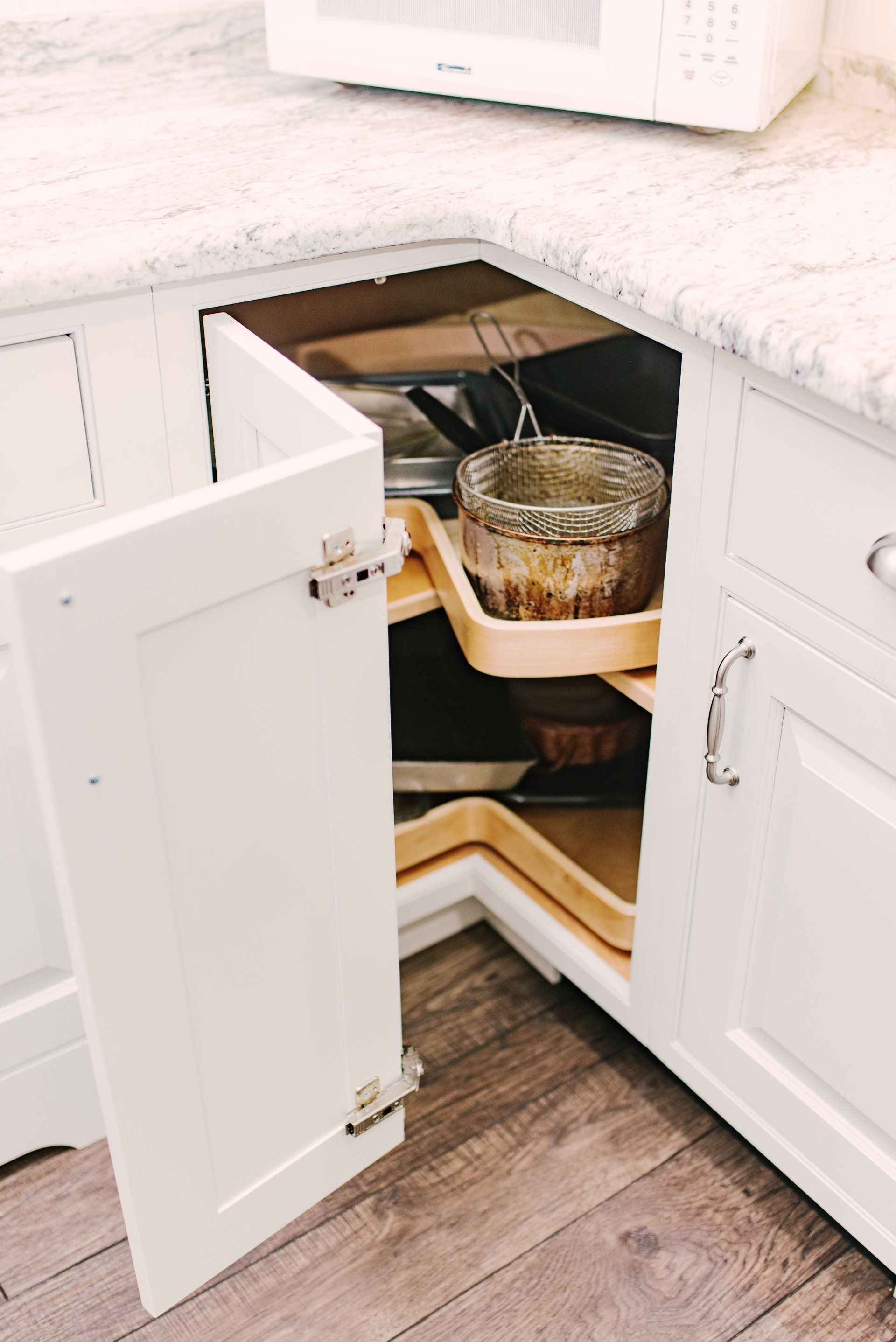 A kitchen with white cabinets and a microwave.