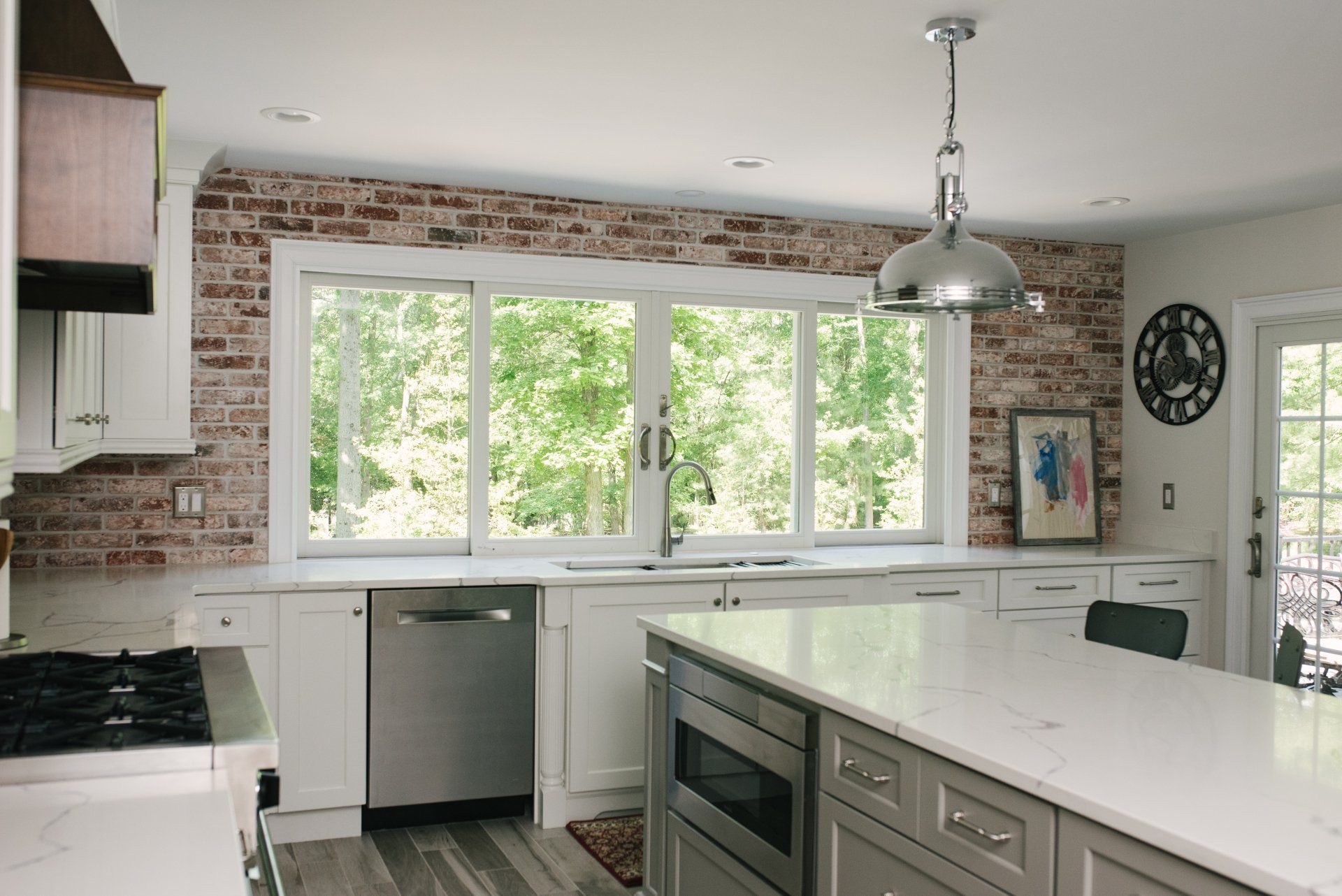 A kitchen with white cabinets , stainless steel appliances , and a large island.