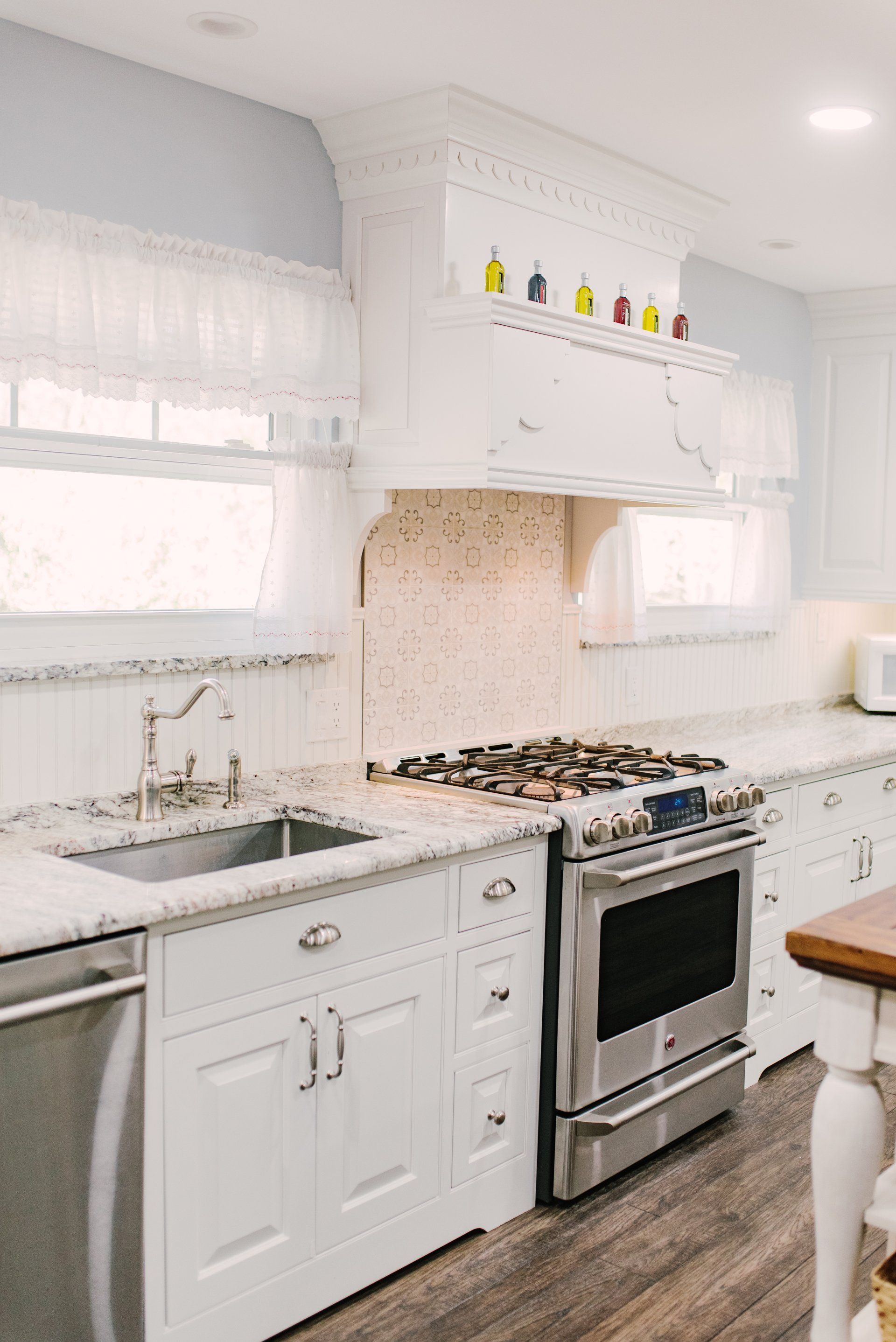 A kitchen with white cabinets , stainless steel appliances , a sink , and a stove.