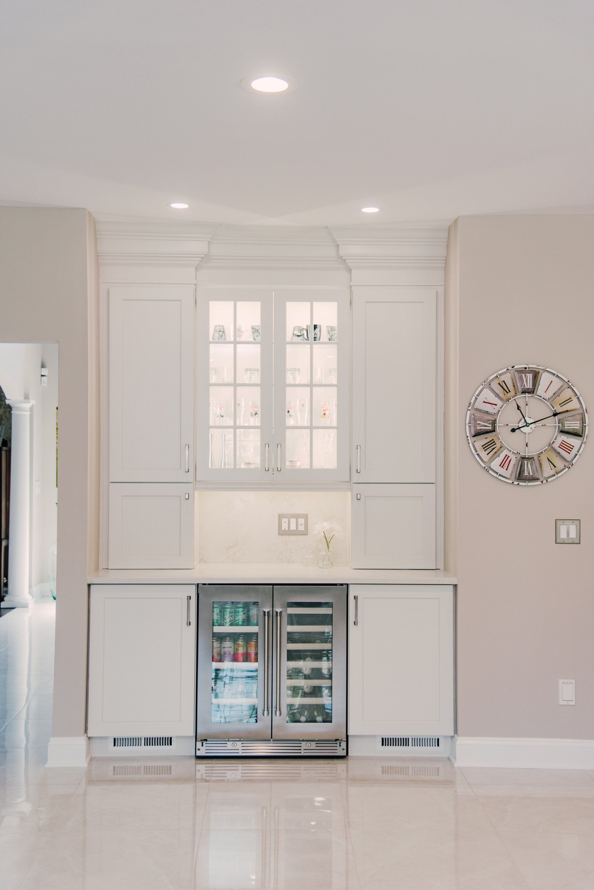 A kitchen with a refrigerator and a clock on the wall.