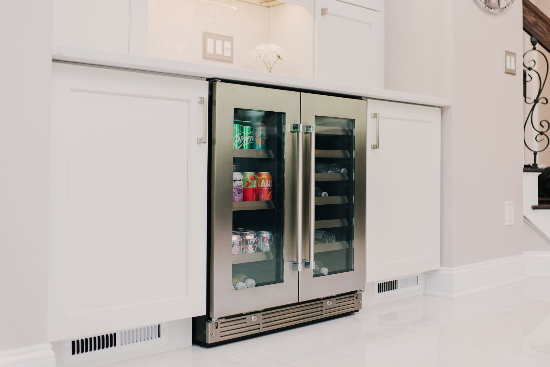 A stainless steel refrigerator with glass doors is in a kitchen.