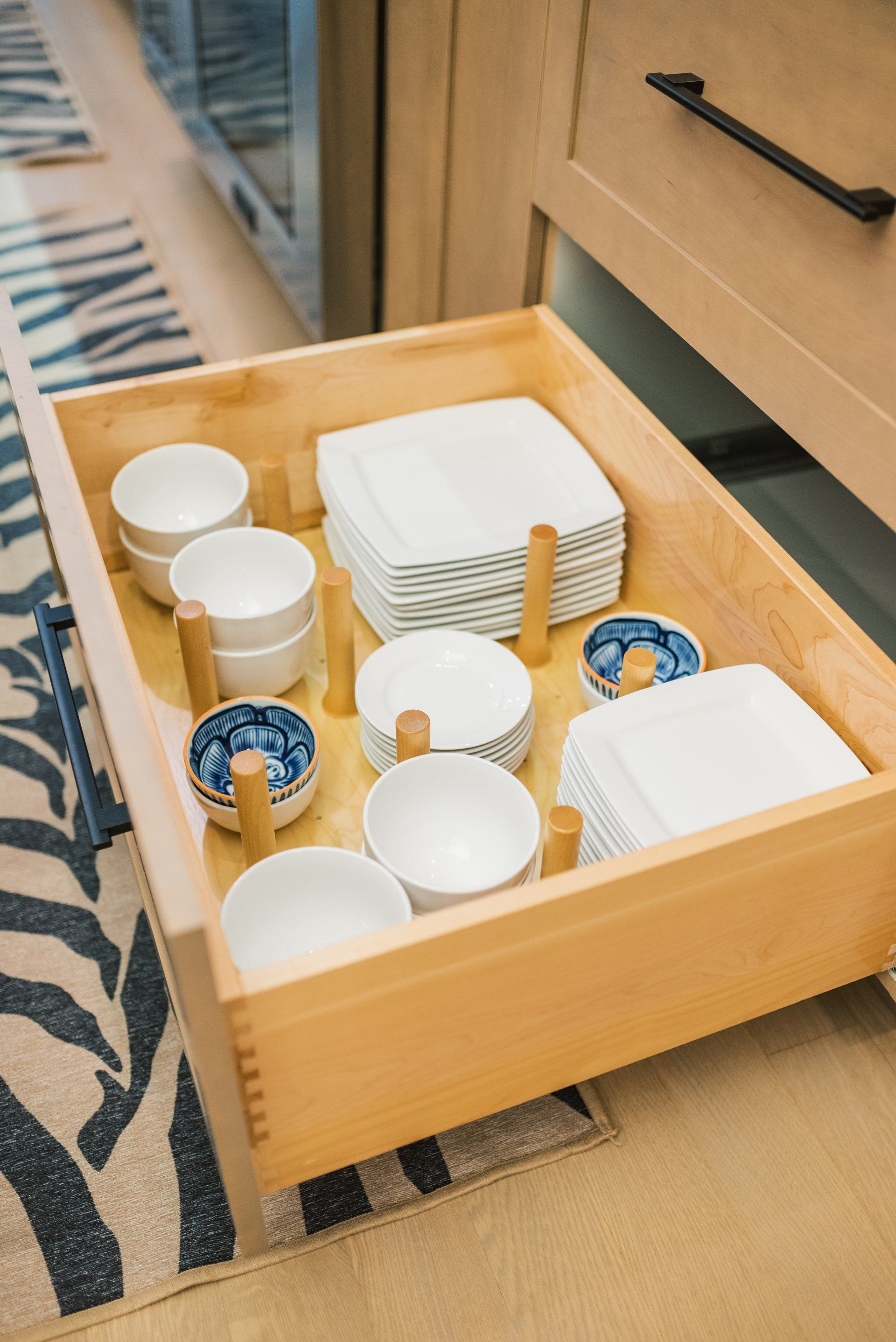 A wooden drawer filled with bowls and plates in a kitchen.