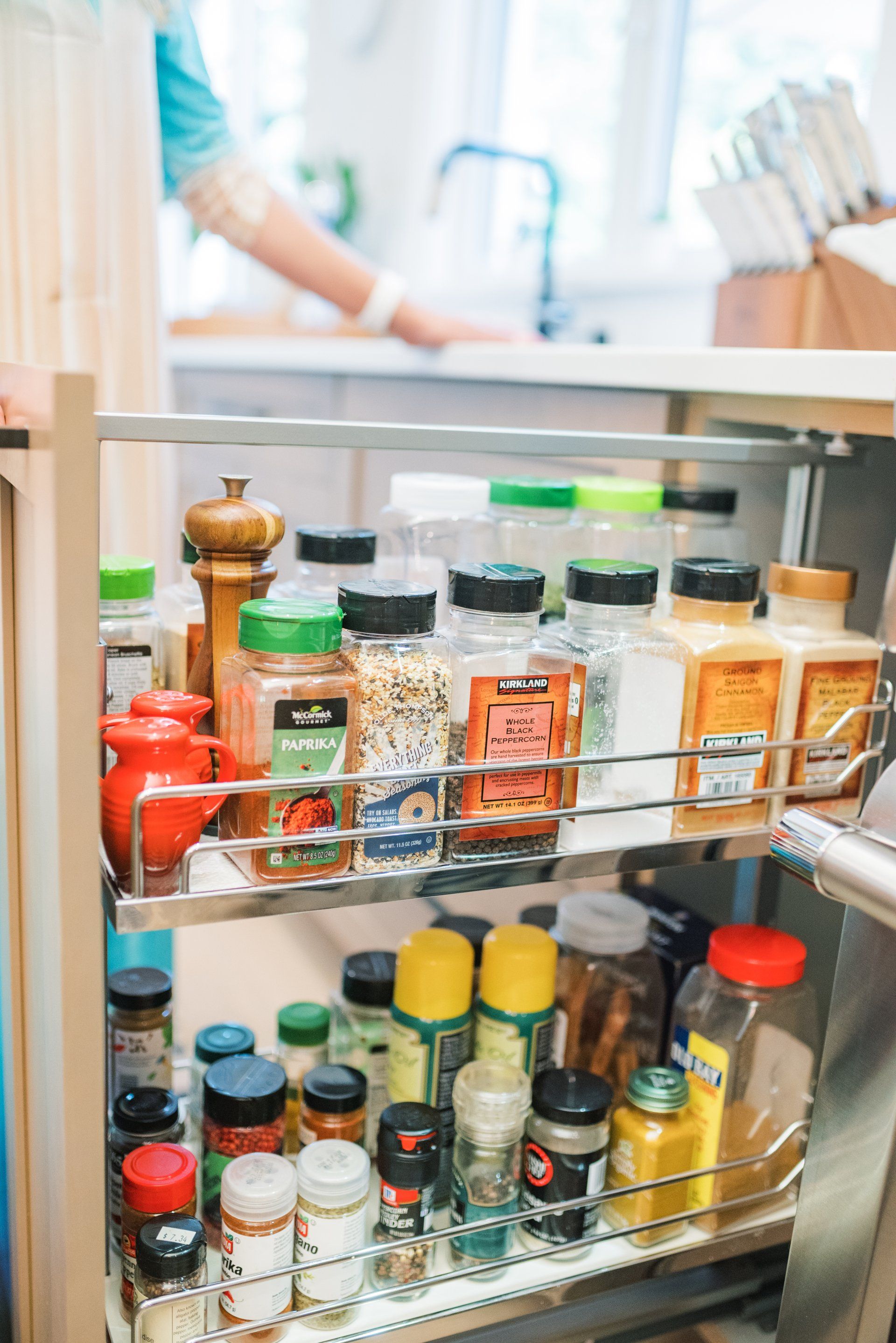 A kitchen cabinet filled with lots of spices and condiments.