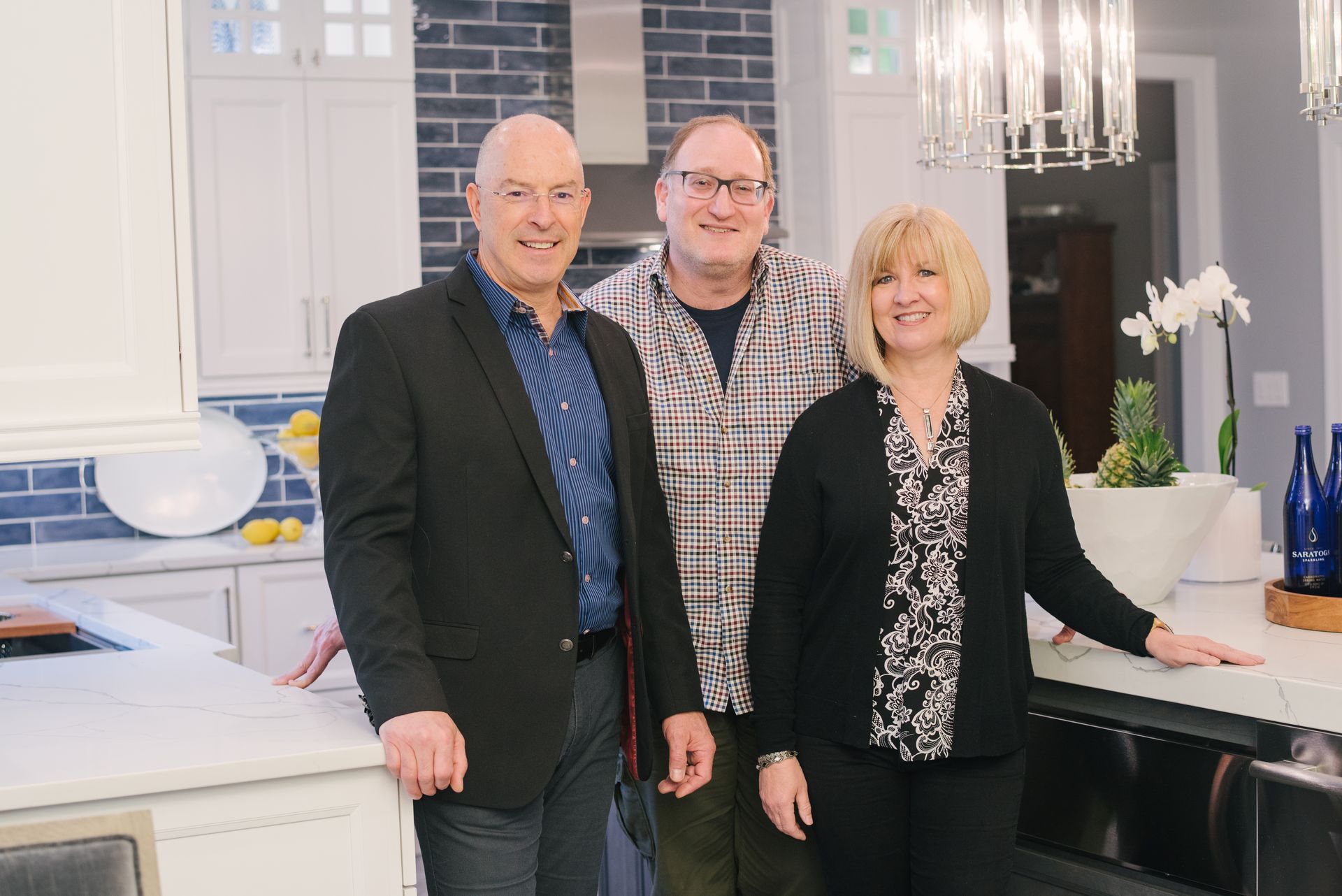 Three people are posing for a picture in a kitchen.
