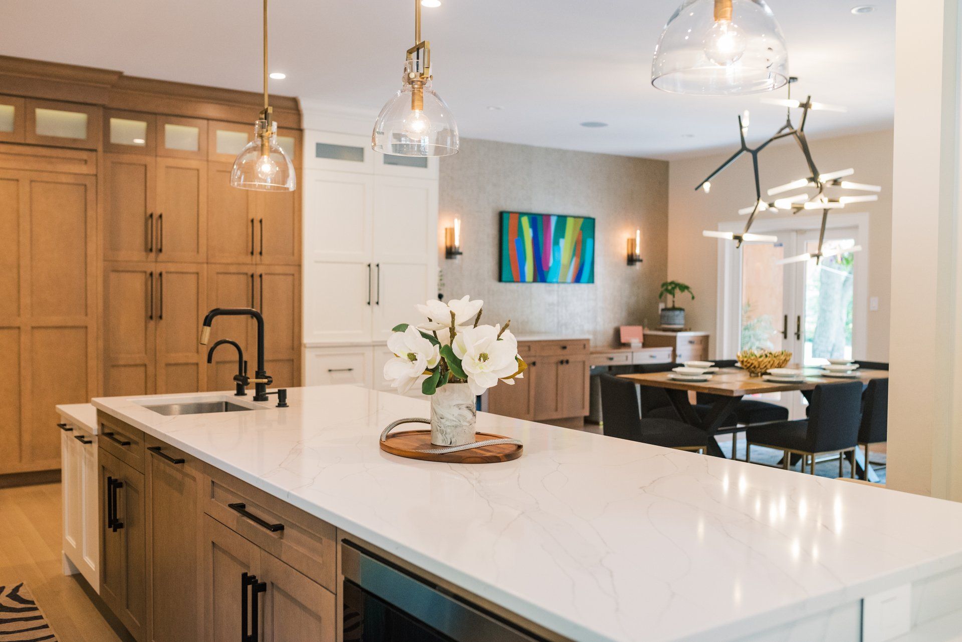 A kitchen with a large island in the middle and a dining room in the background.