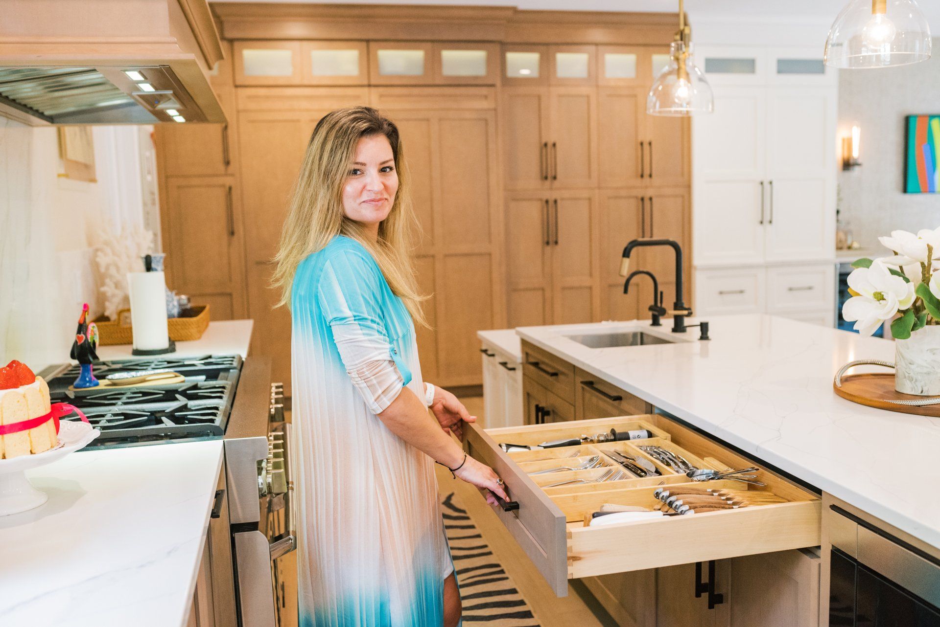 A woman is opening a drawer in a kitchen.